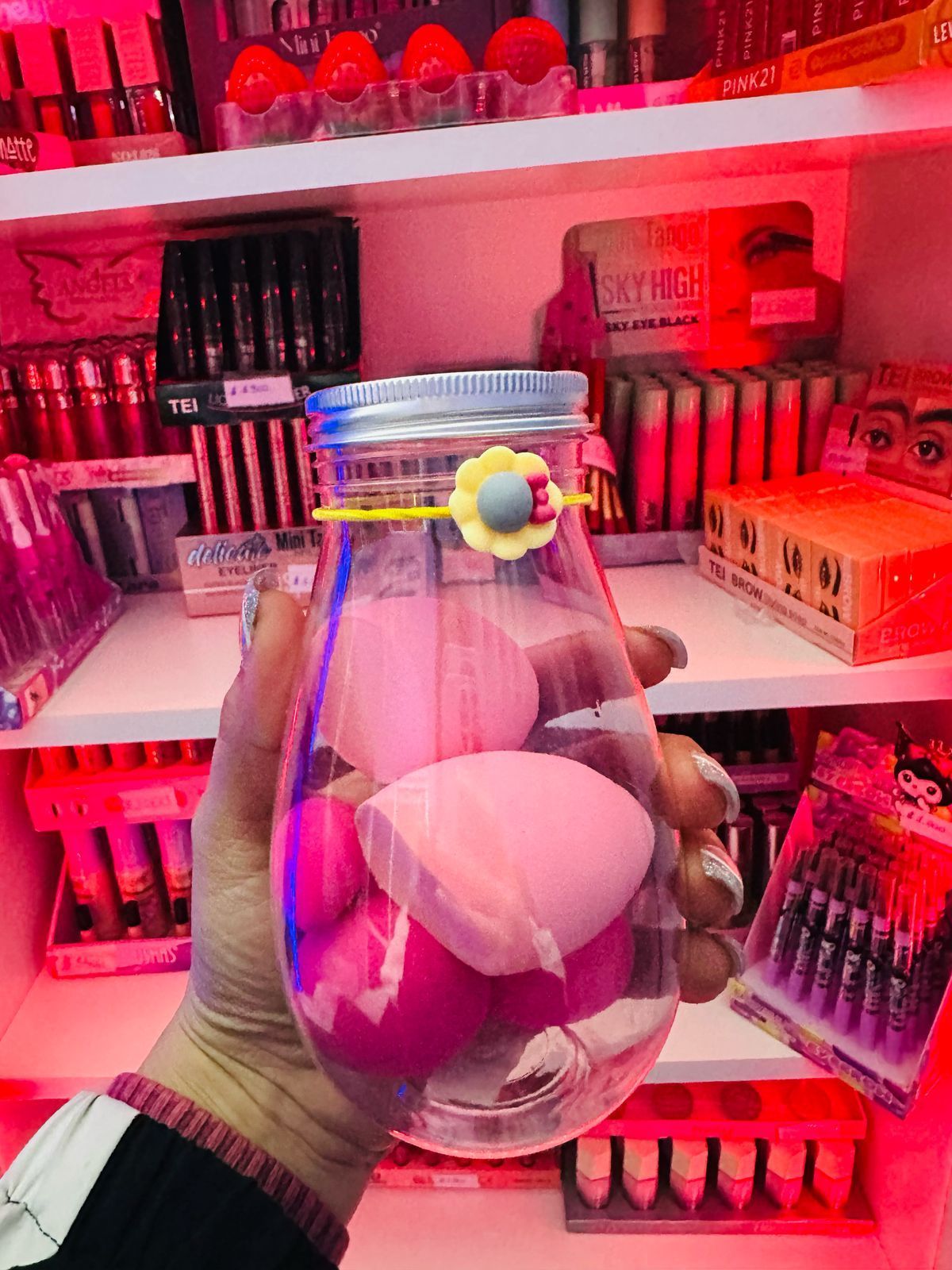 Una persona sostiene un vaso lleno de esponjas de maquillaje.