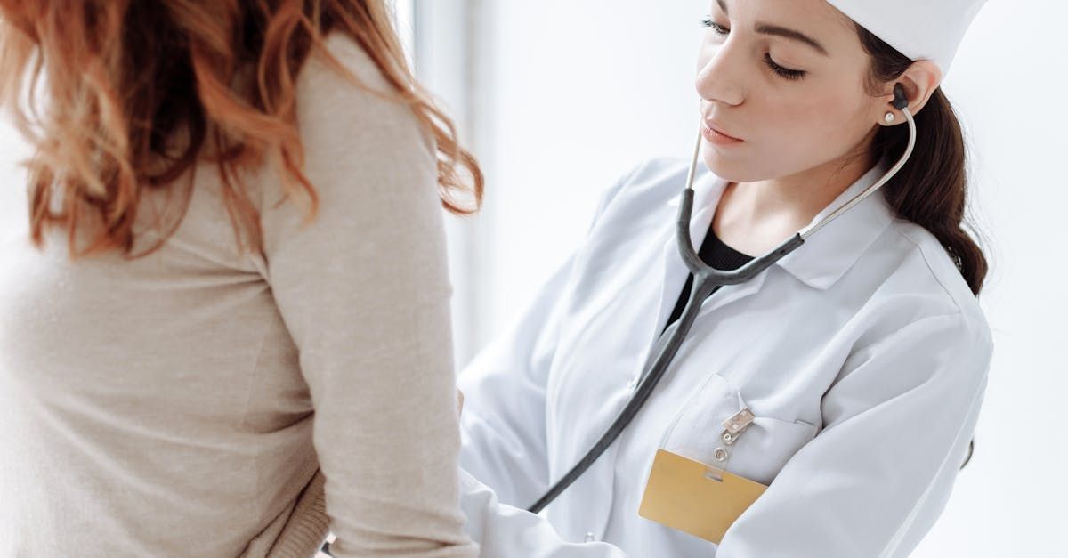 A doctor is listening to a patient 's heartbeat with a stethoscope.