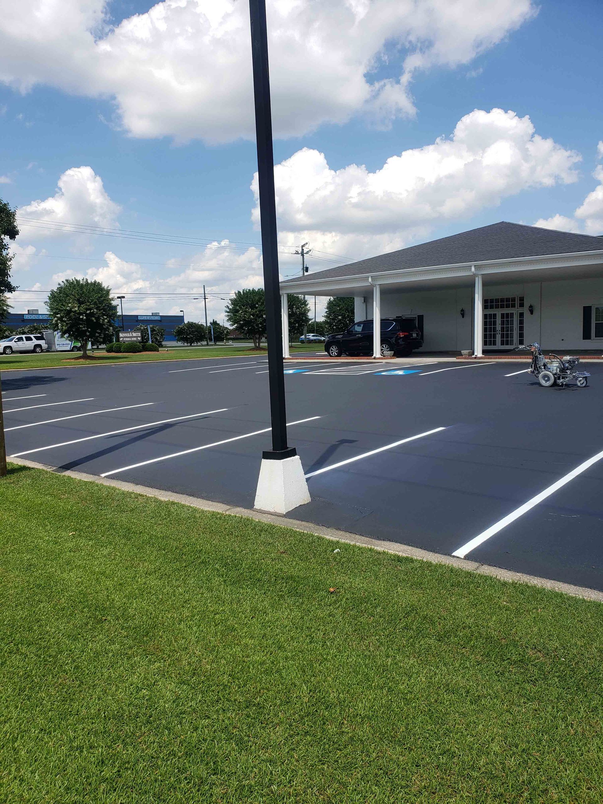 A parking lot with a building in the background on a sunny day.