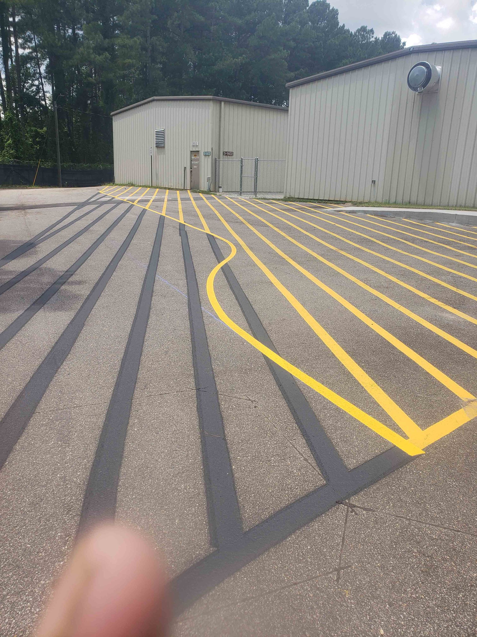 A person is pointing at a parking lot with yellow lines painted on it.