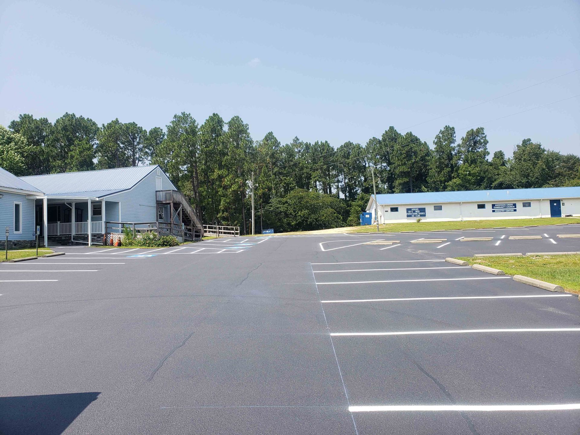 A parking lot with a building in the background and trees in the background.