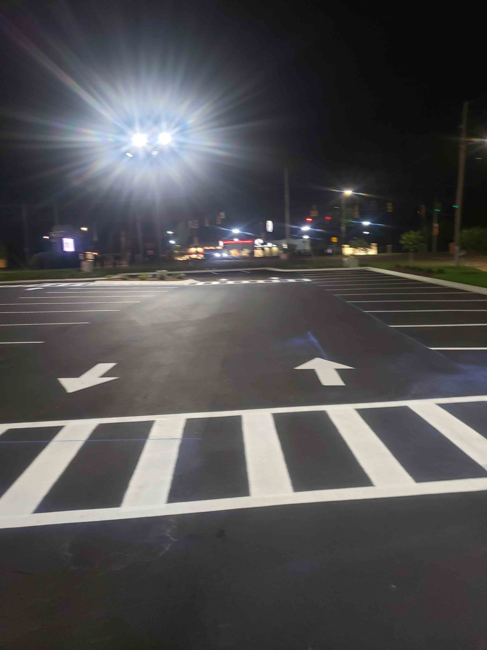 A parking lot with arrows painted on it at night.