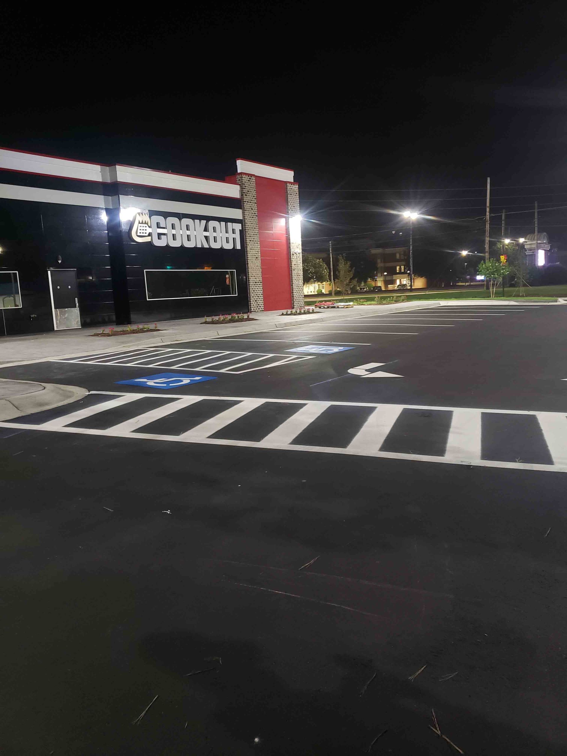 A parking lot with a building in the background at night.