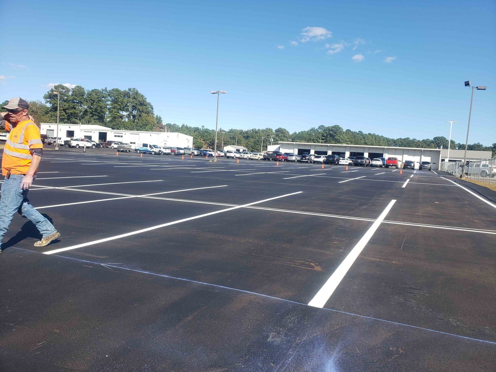 A man in an orange shirt walks through a parking lot