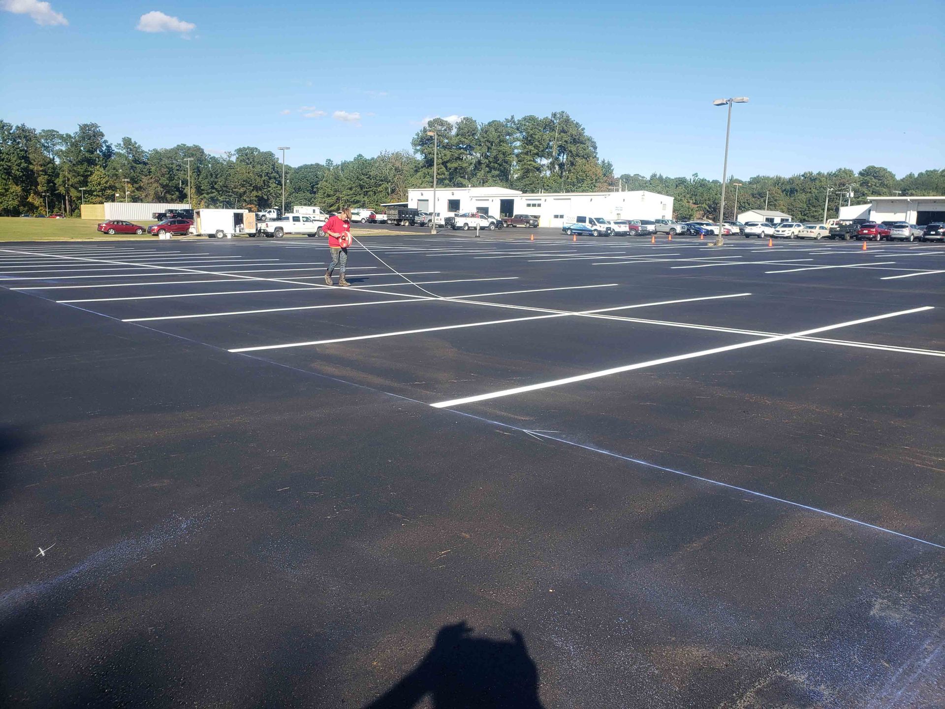 A man in a red shirt is standing in a parking lot.