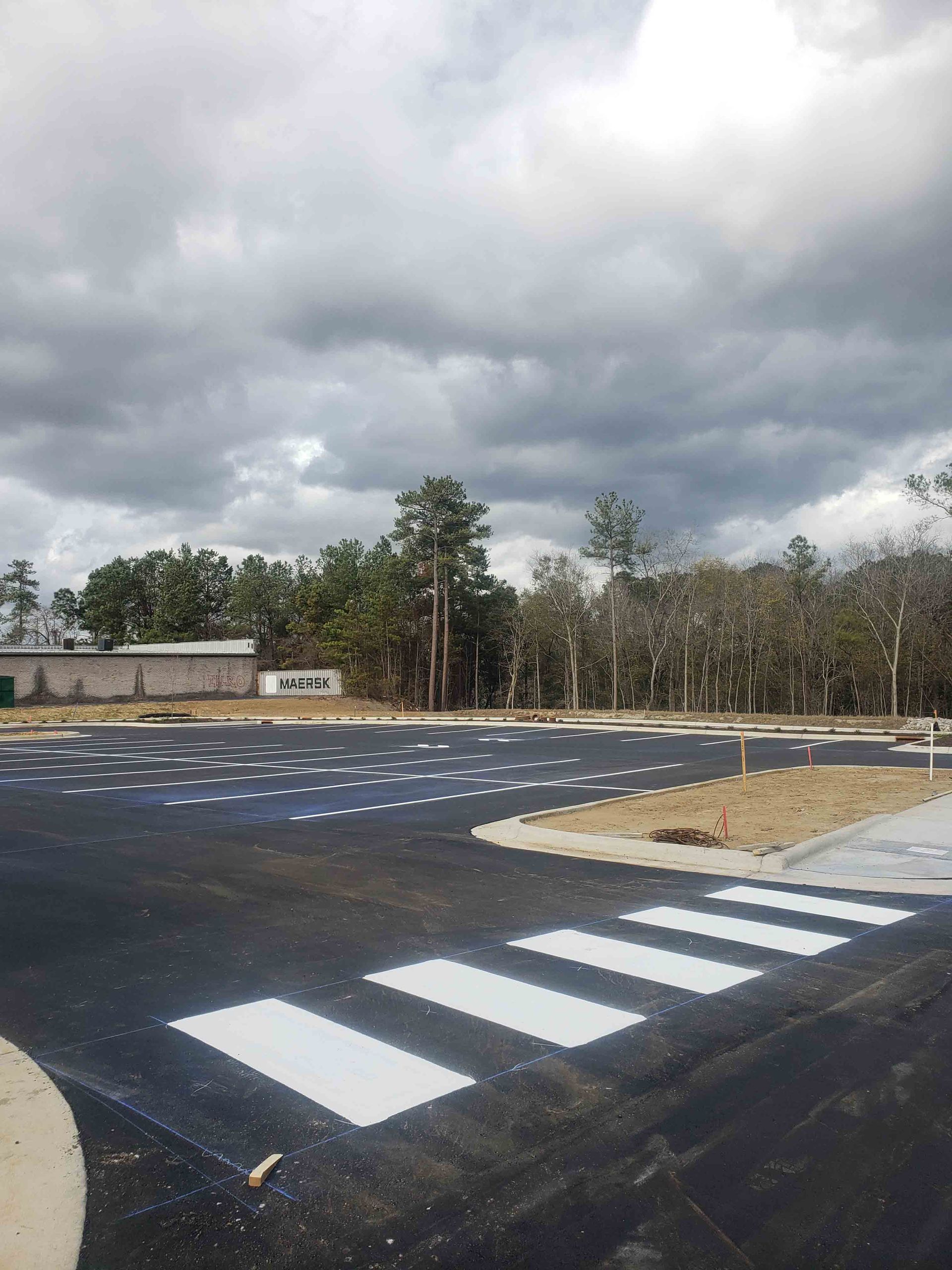 A parking lot with a crosswalk and trees in the background.