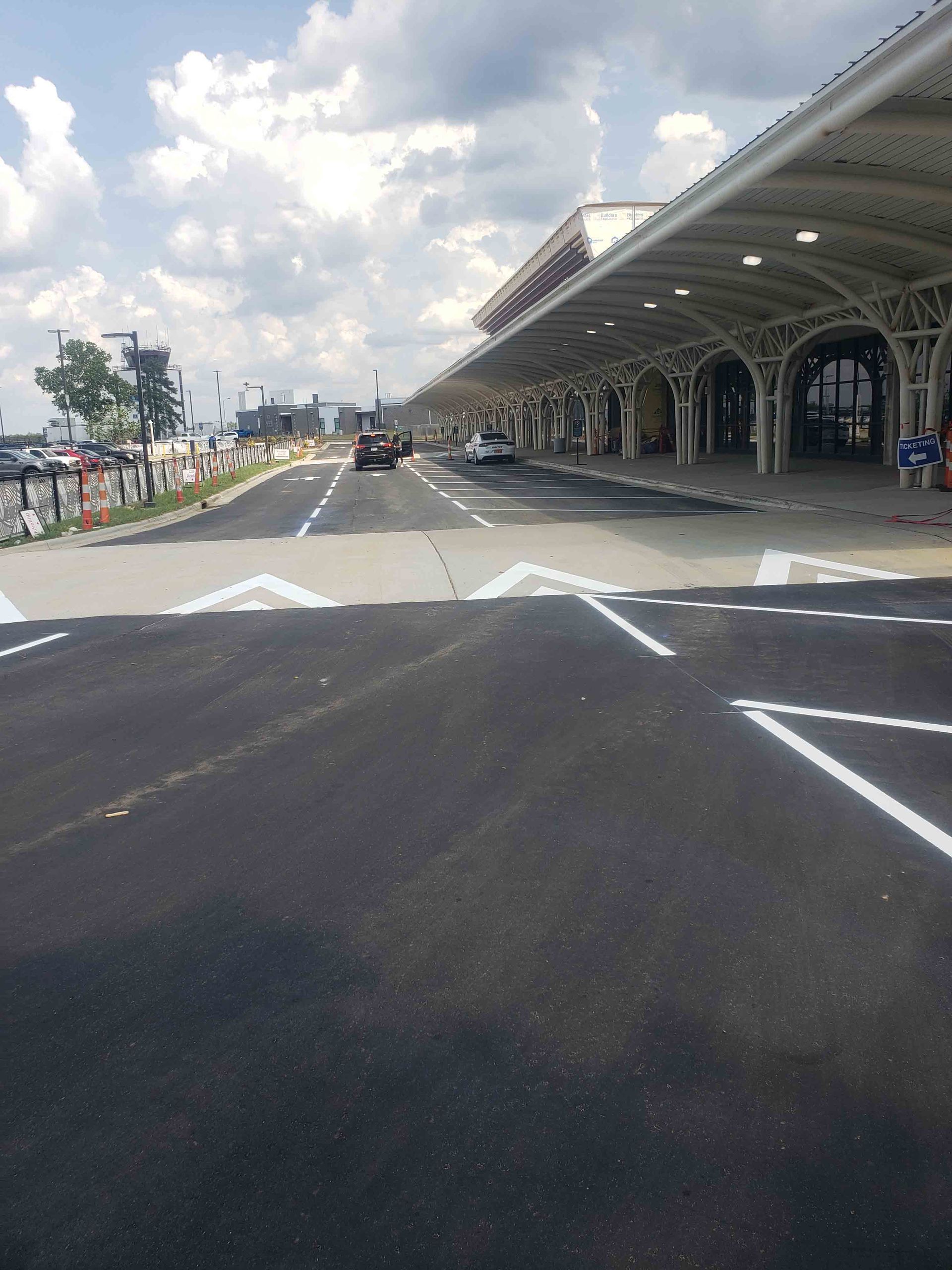 A parking lot at an airport with cars parked under a canopy.