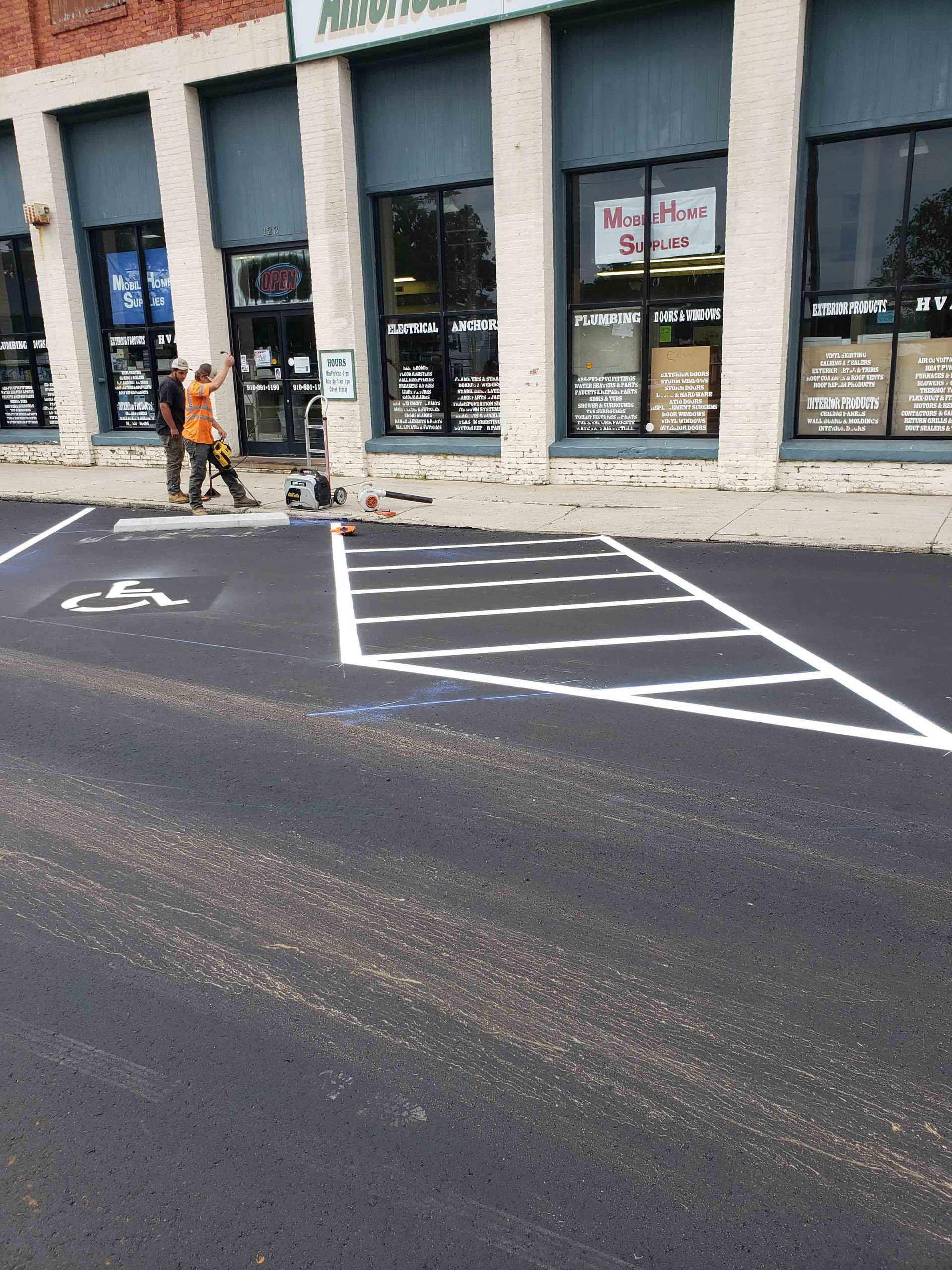 A handicapped parking spot is being painted in front of a building