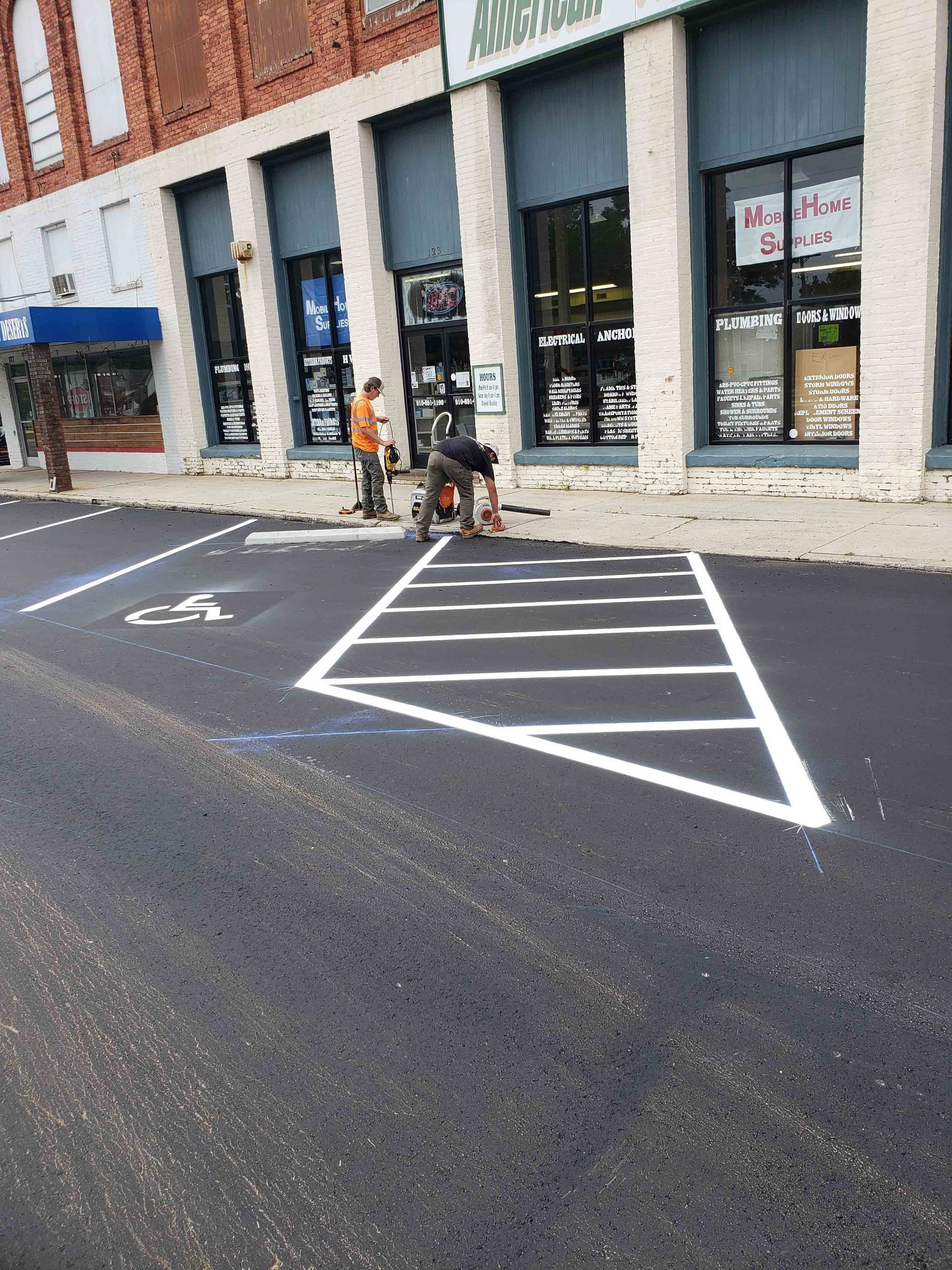 A man is painting a handicapped parking space in front of a building.