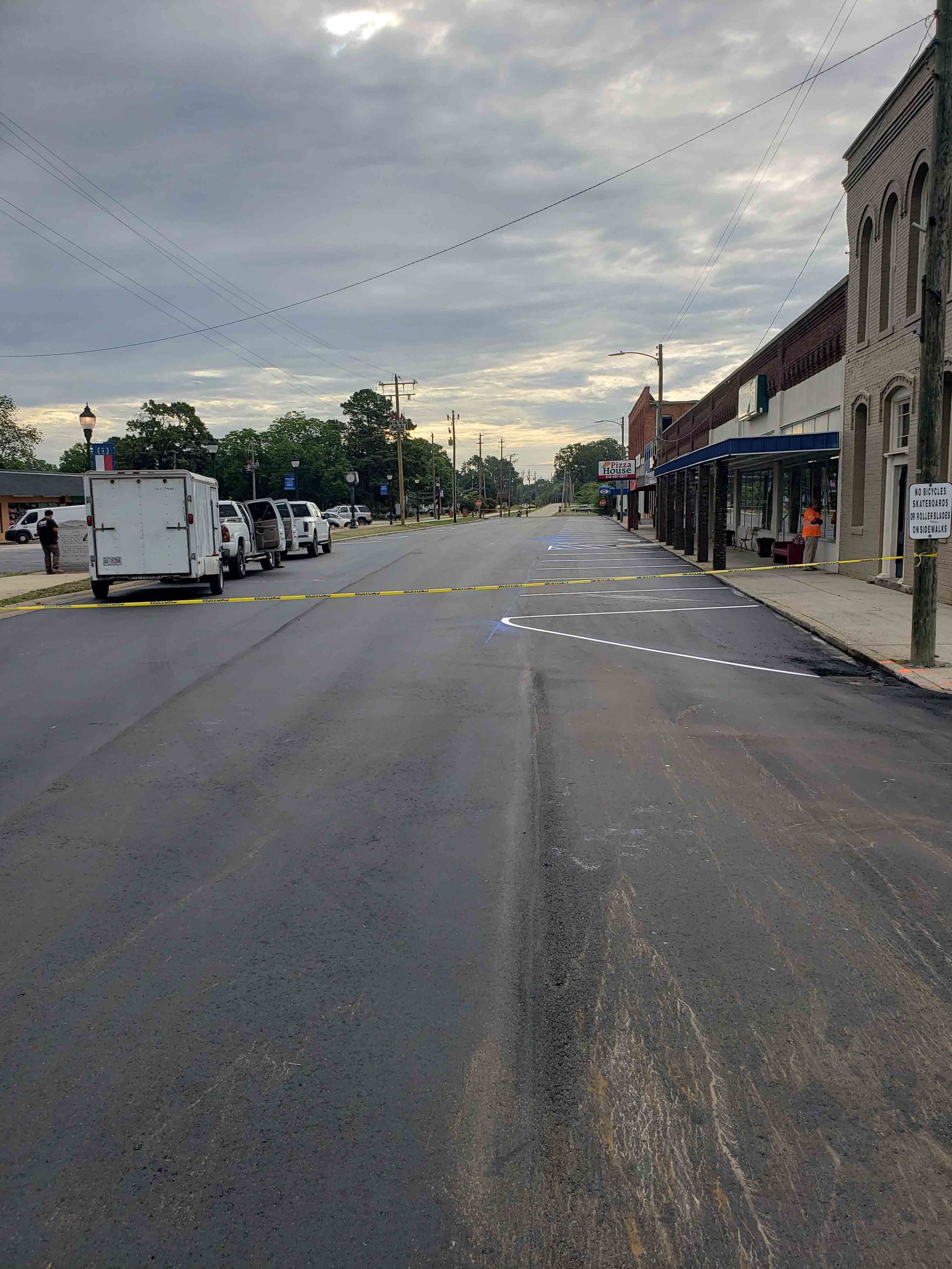 A row of trucks are parked on the side of a street in a small town.