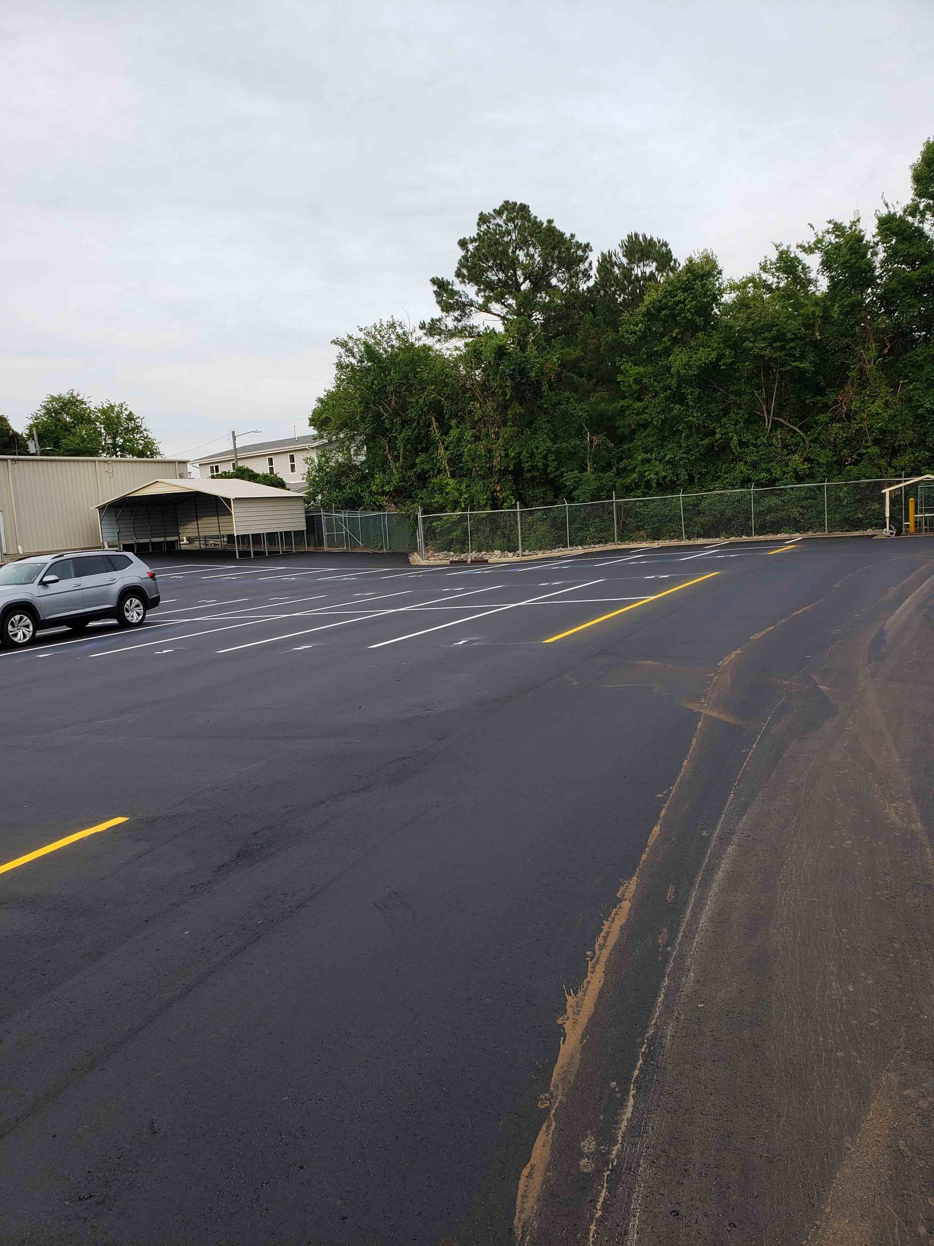 A car is parked in a parking lot with trees in the background