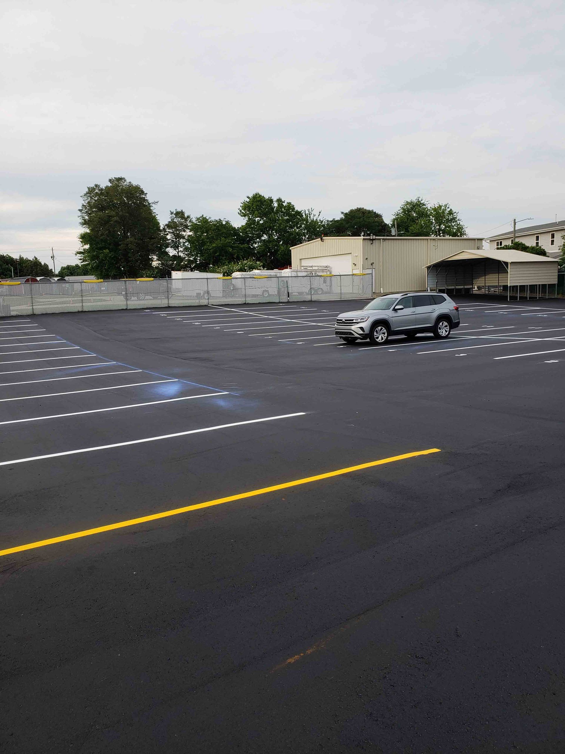 A car is driving down an empty parking lot