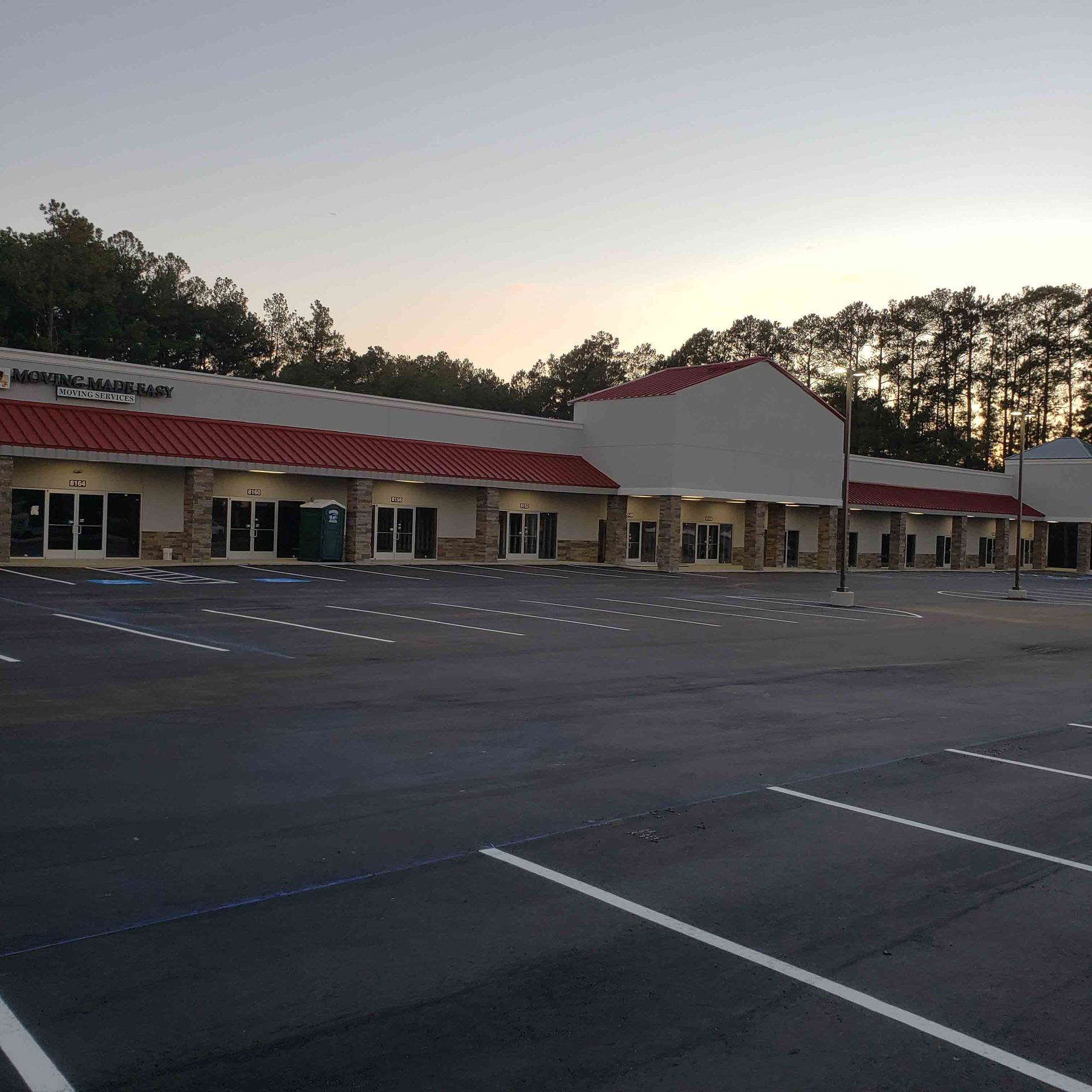 A parking lot in front of a building with a red roof