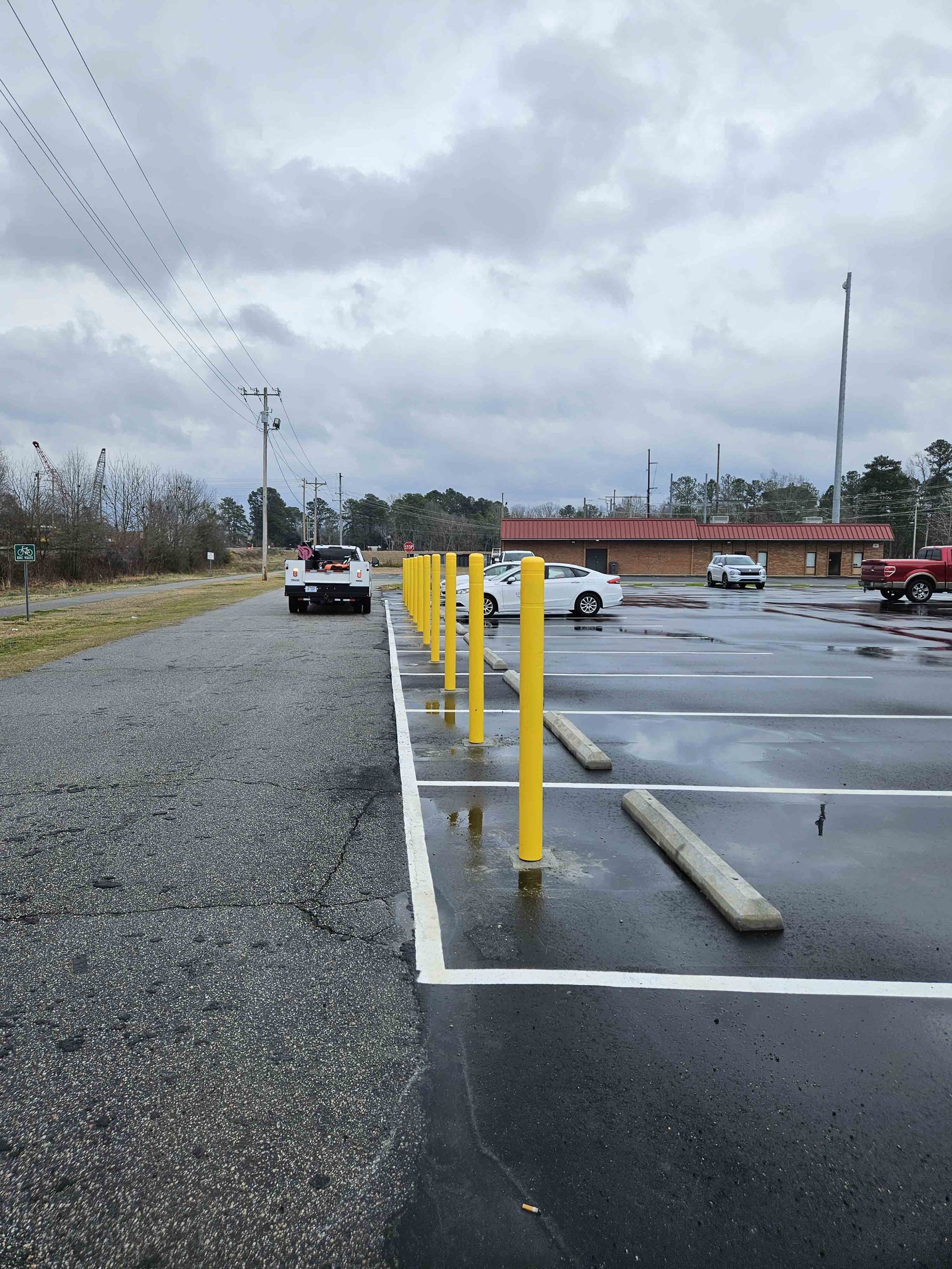 A parking lot with yellow poles and cars parked in it