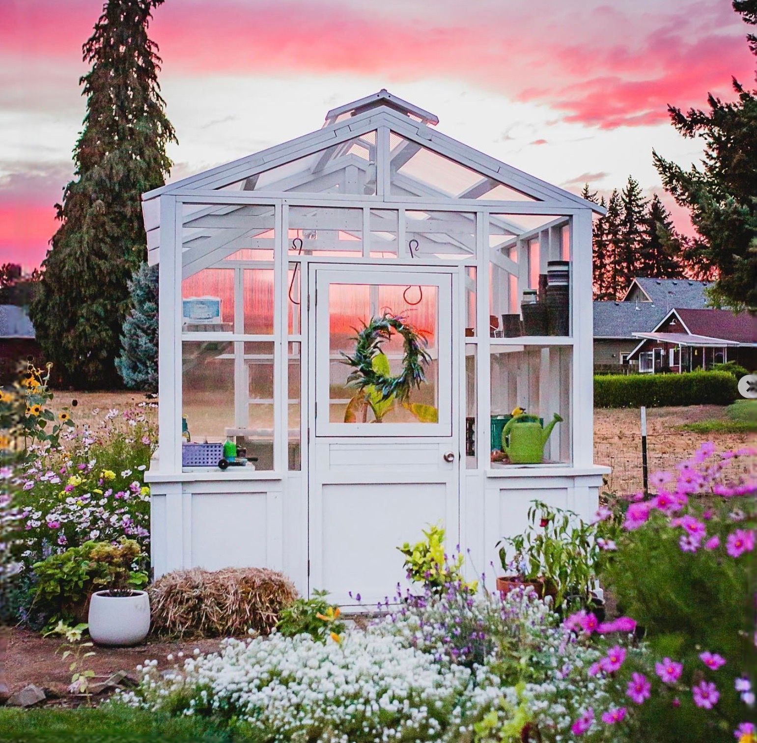 A white greenhouse with a wreath on the door