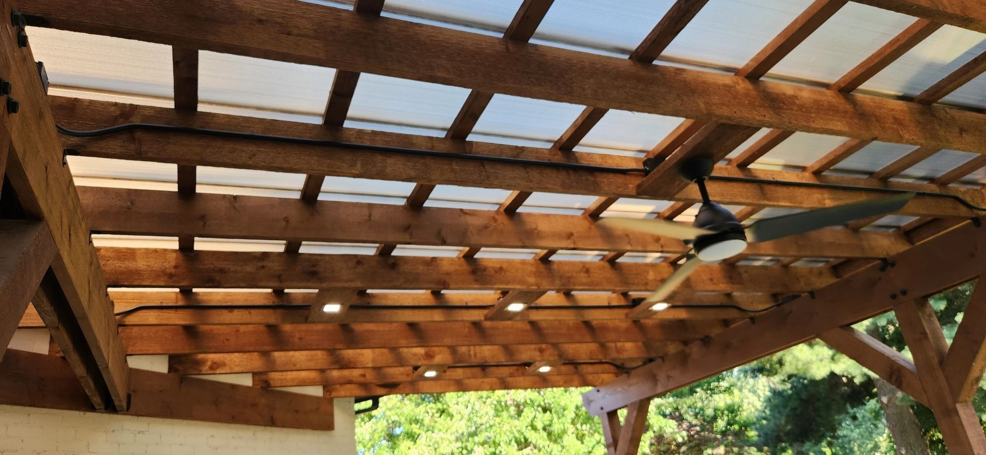 A ceiling fan is hanging from the ceiling of a wooden structure.