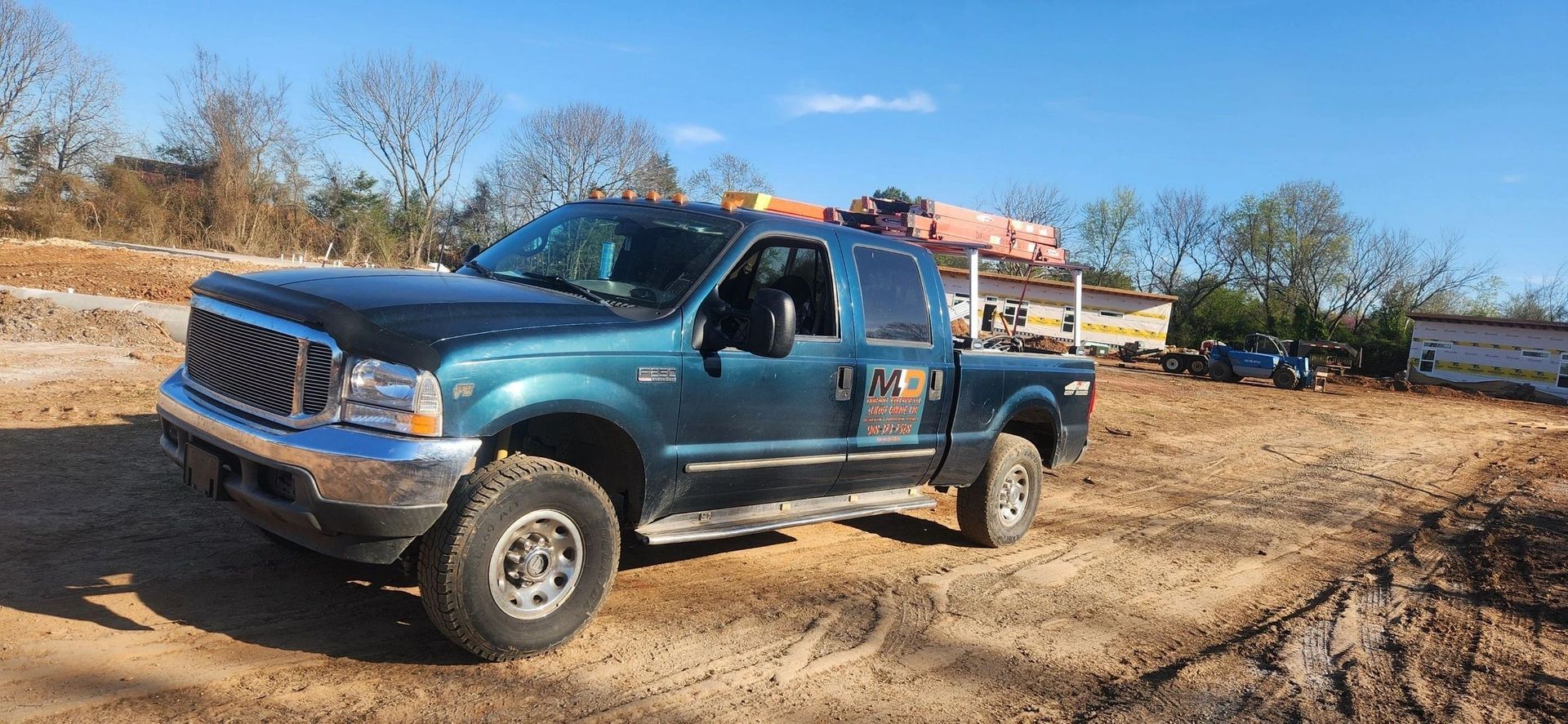 A blue pickup truck is parked in a dirt field.