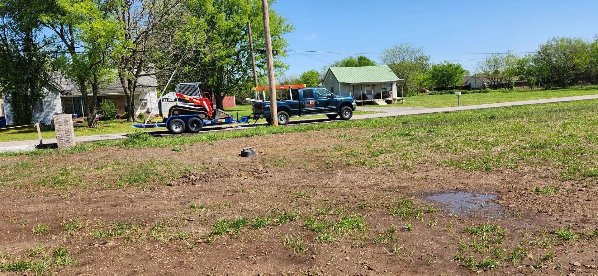 A truck is parked in a grassy field next to a house.
