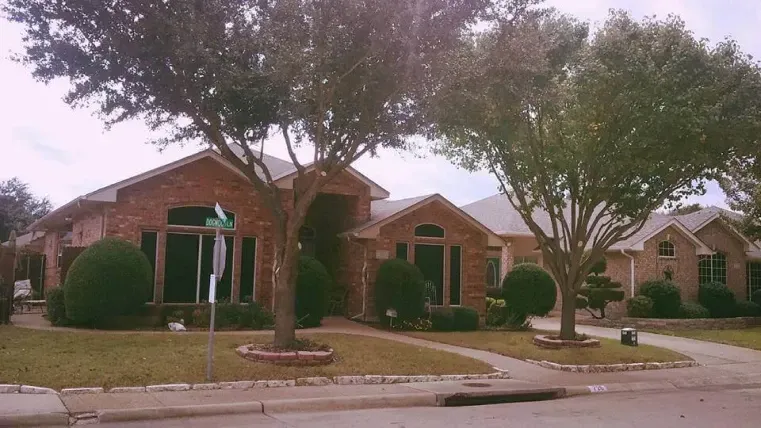 A brick house with a green street sign in front of it