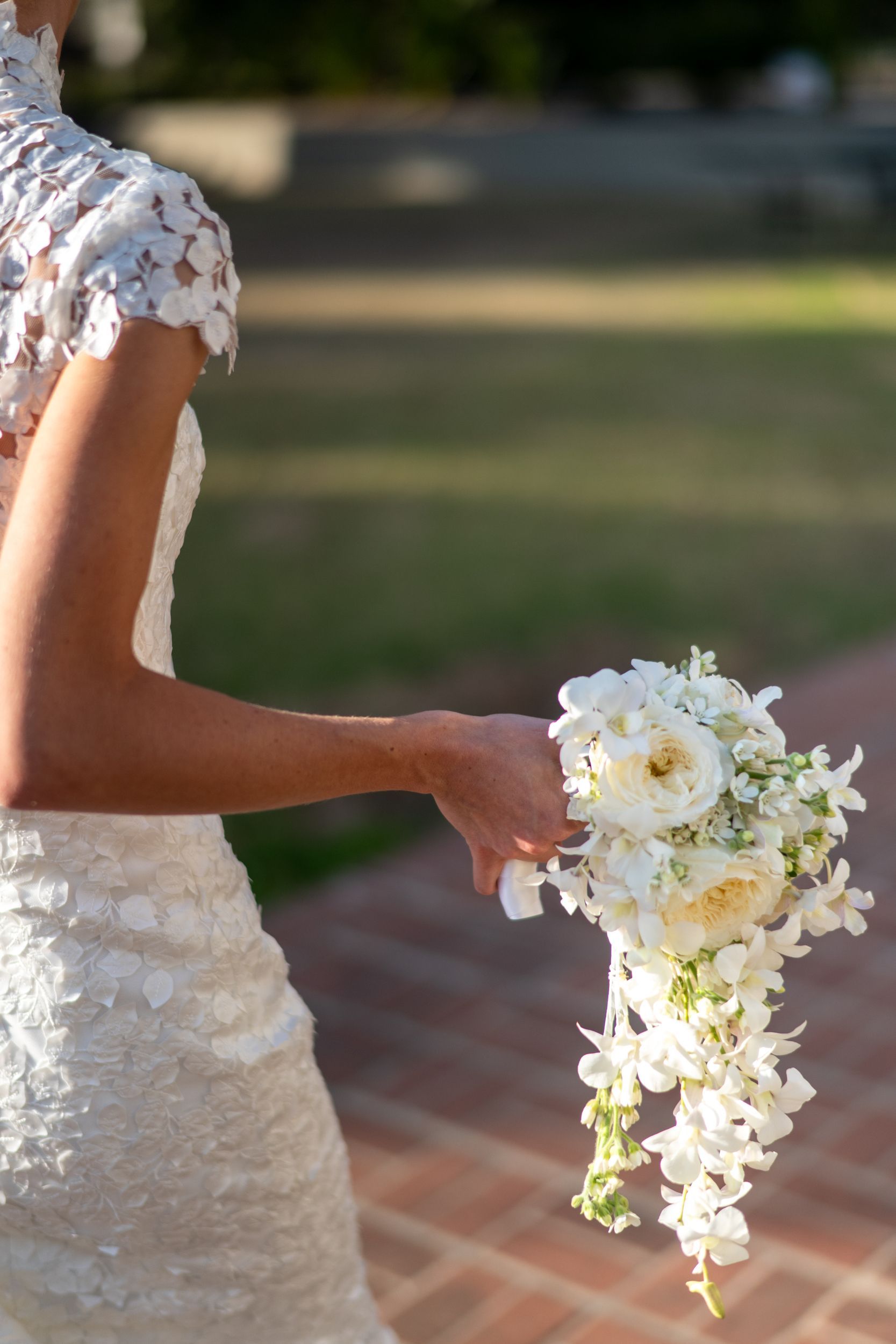 A bride in a wedding dress is holding a bouquet of white flowers