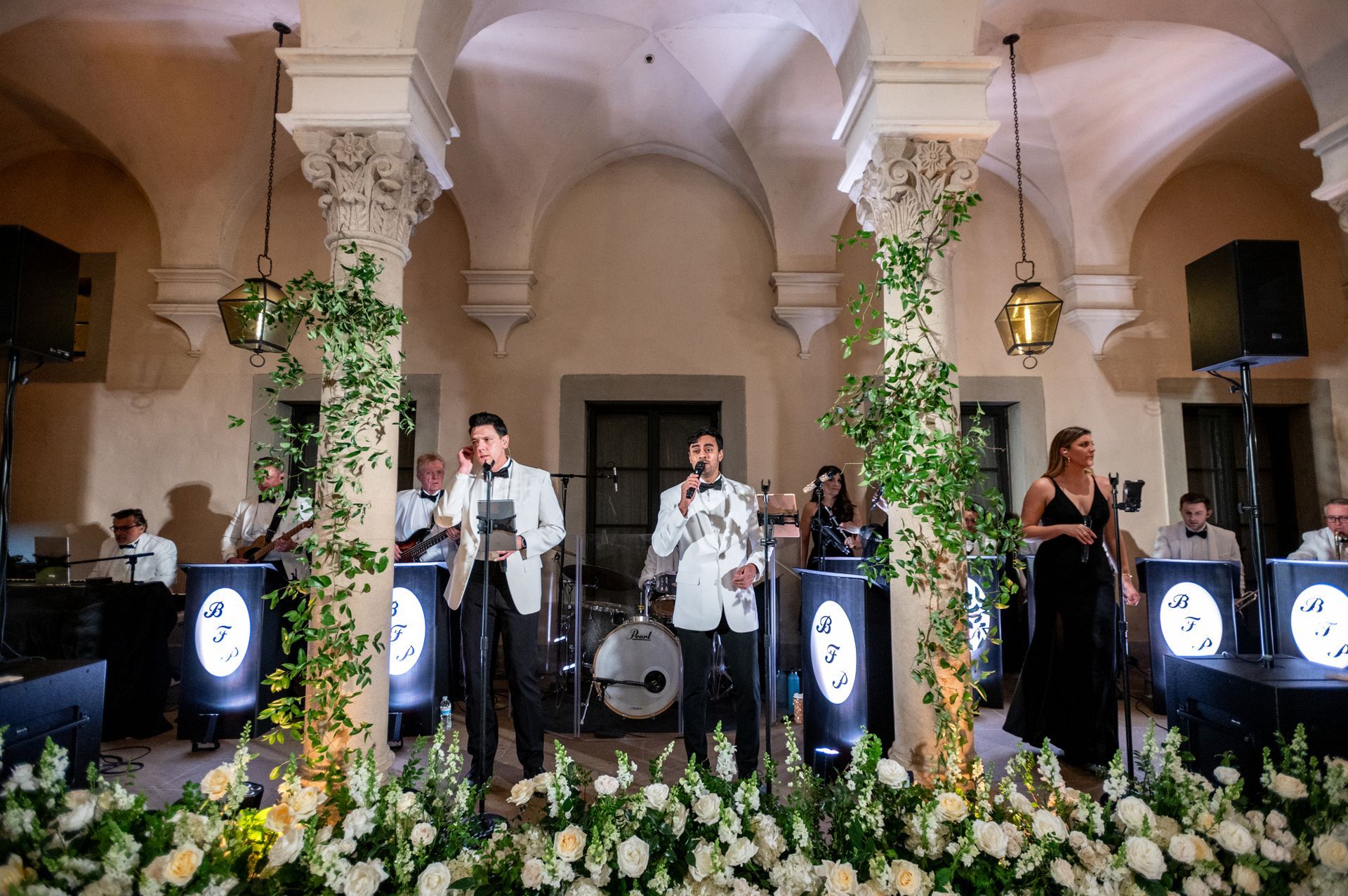 A group of people are standing on a stage with flowers in the background.