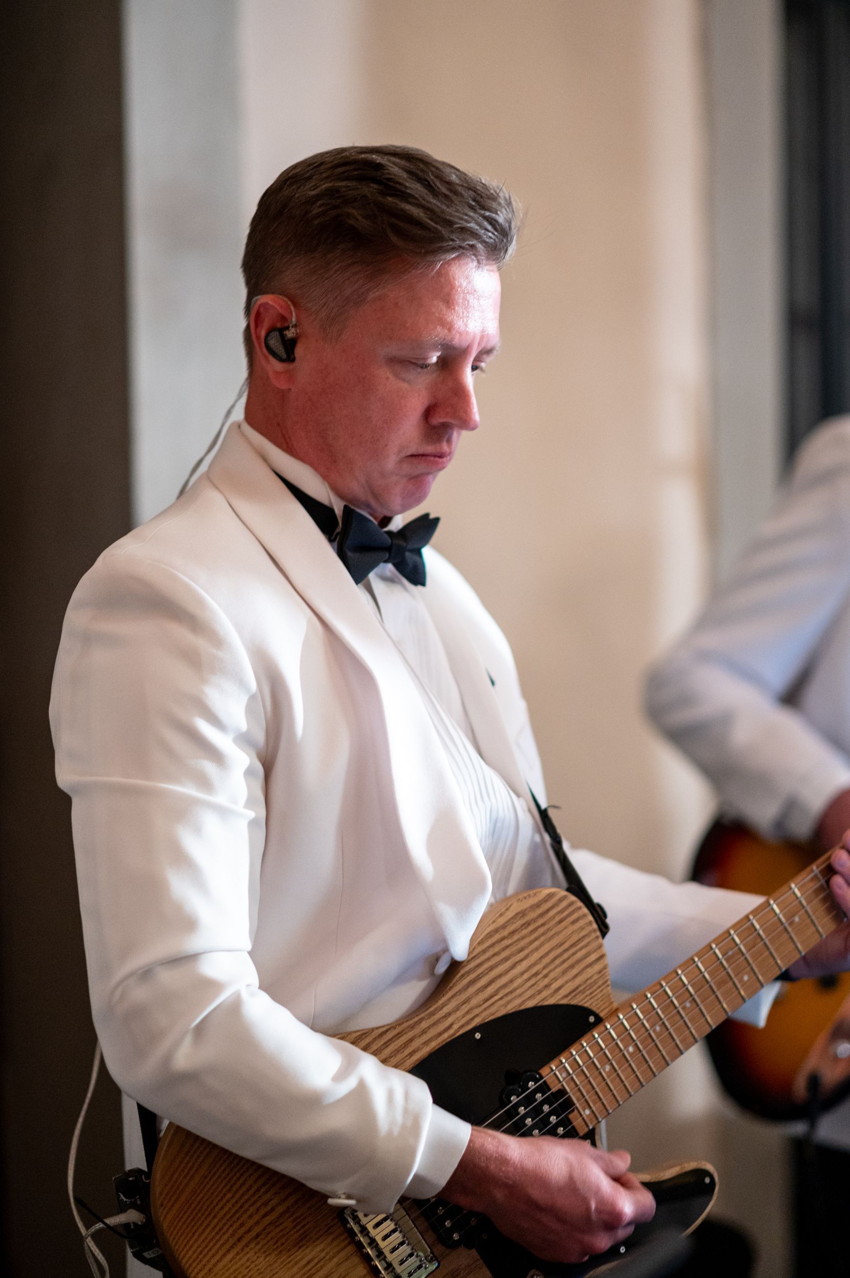 A man in a tuxedo is playing a guitar.