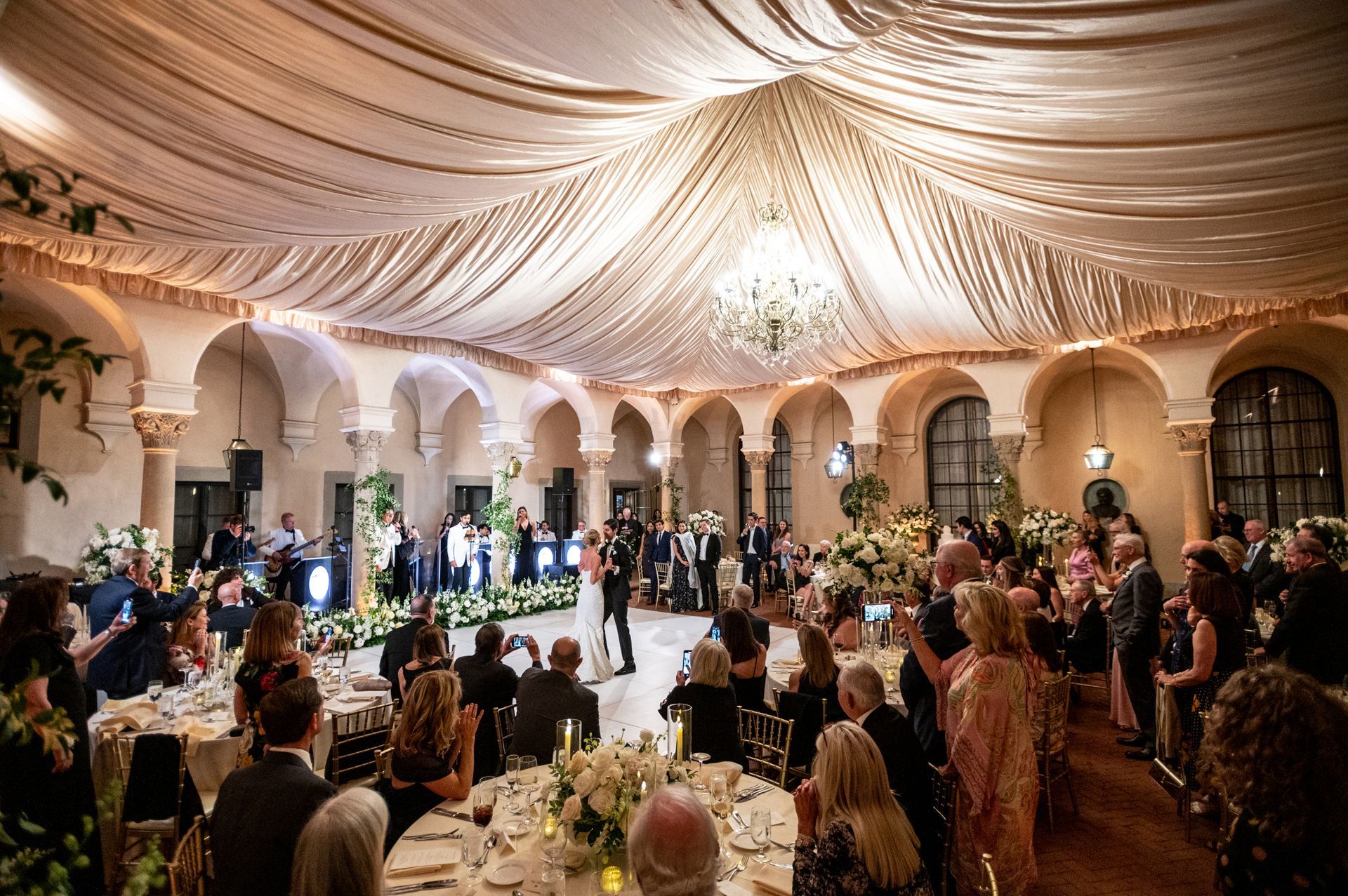 A group of people are sitting at tables in a large room at a wedding reception.