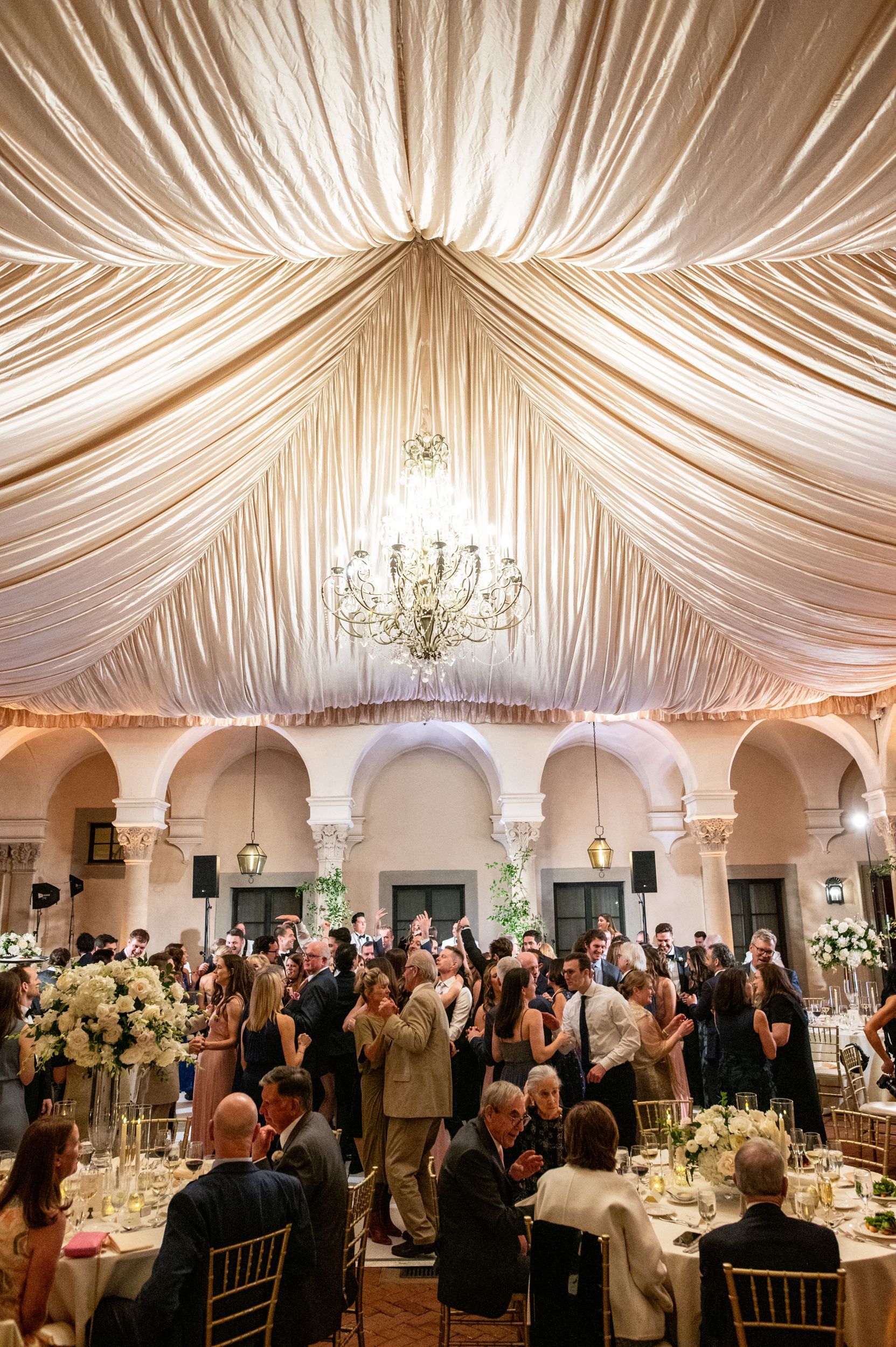 A large group of people are sitting at tables under a tent at a wedding reception.
