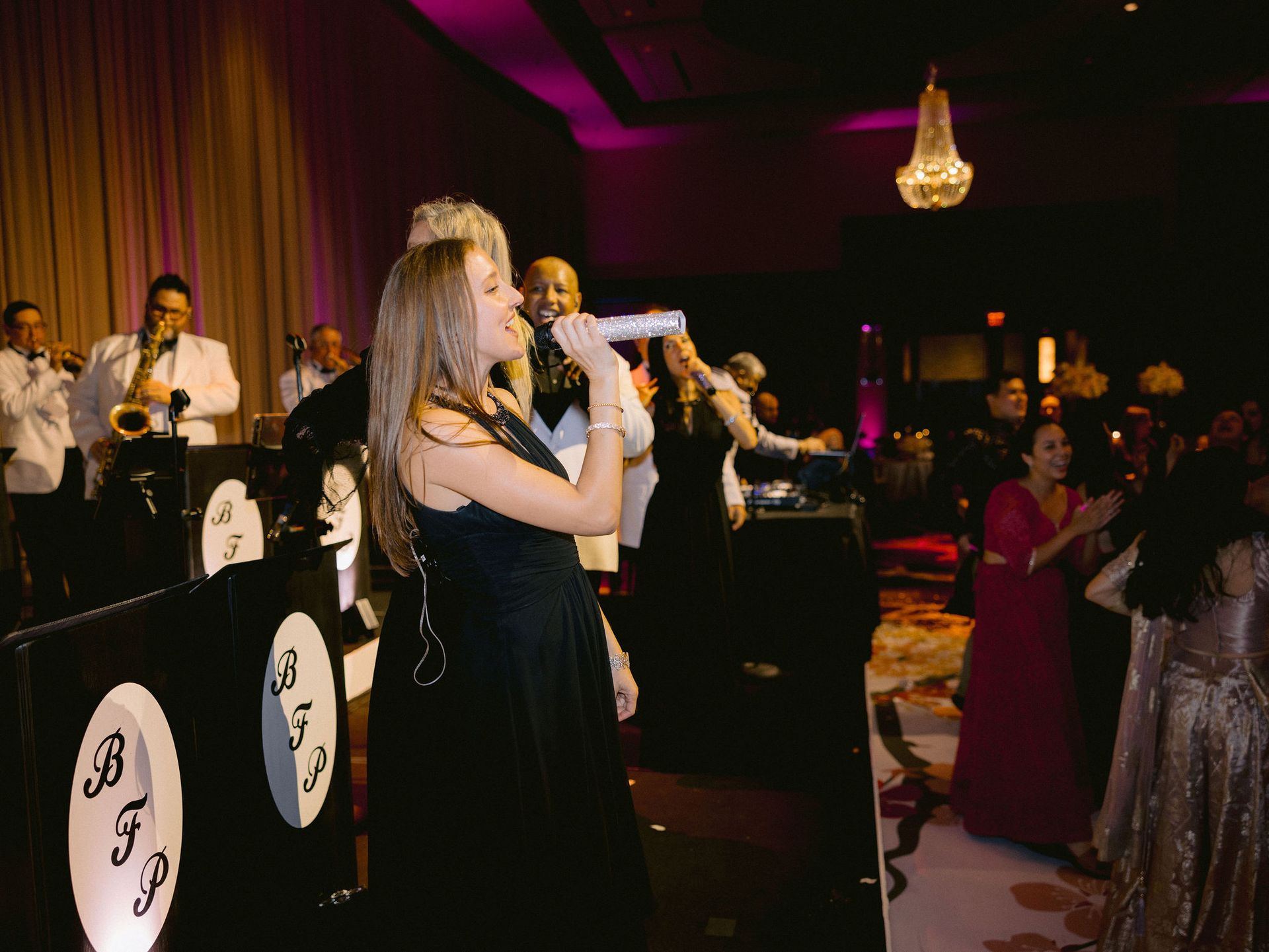A woman is singing into a microphone at a wedding reception.