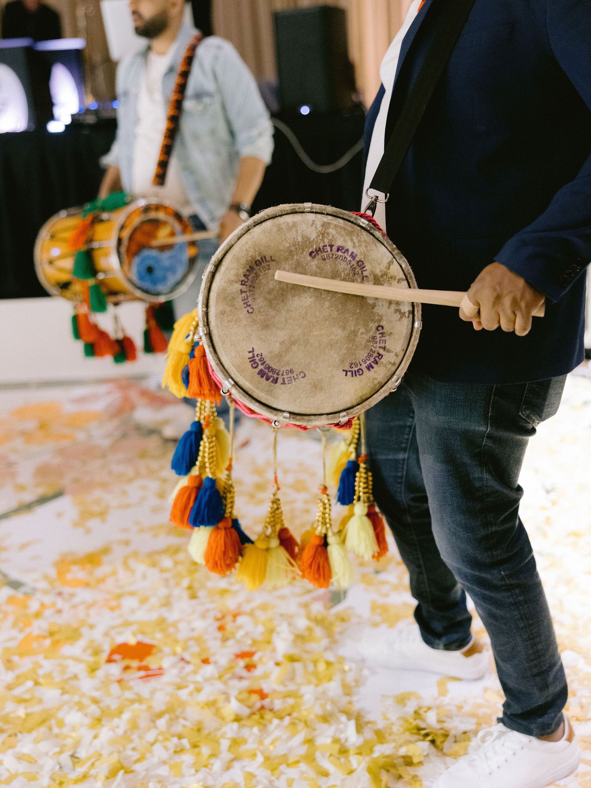 A man is playing a drum with wooden sticks.