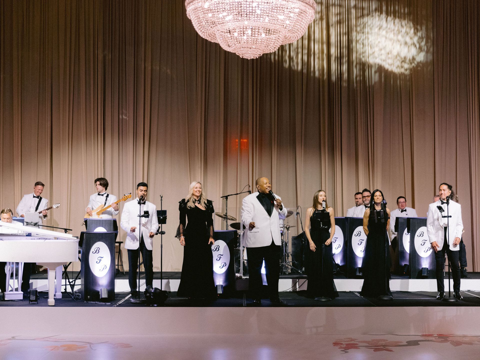 A group of people are standing on a stage playing instruments and singing into microphones.