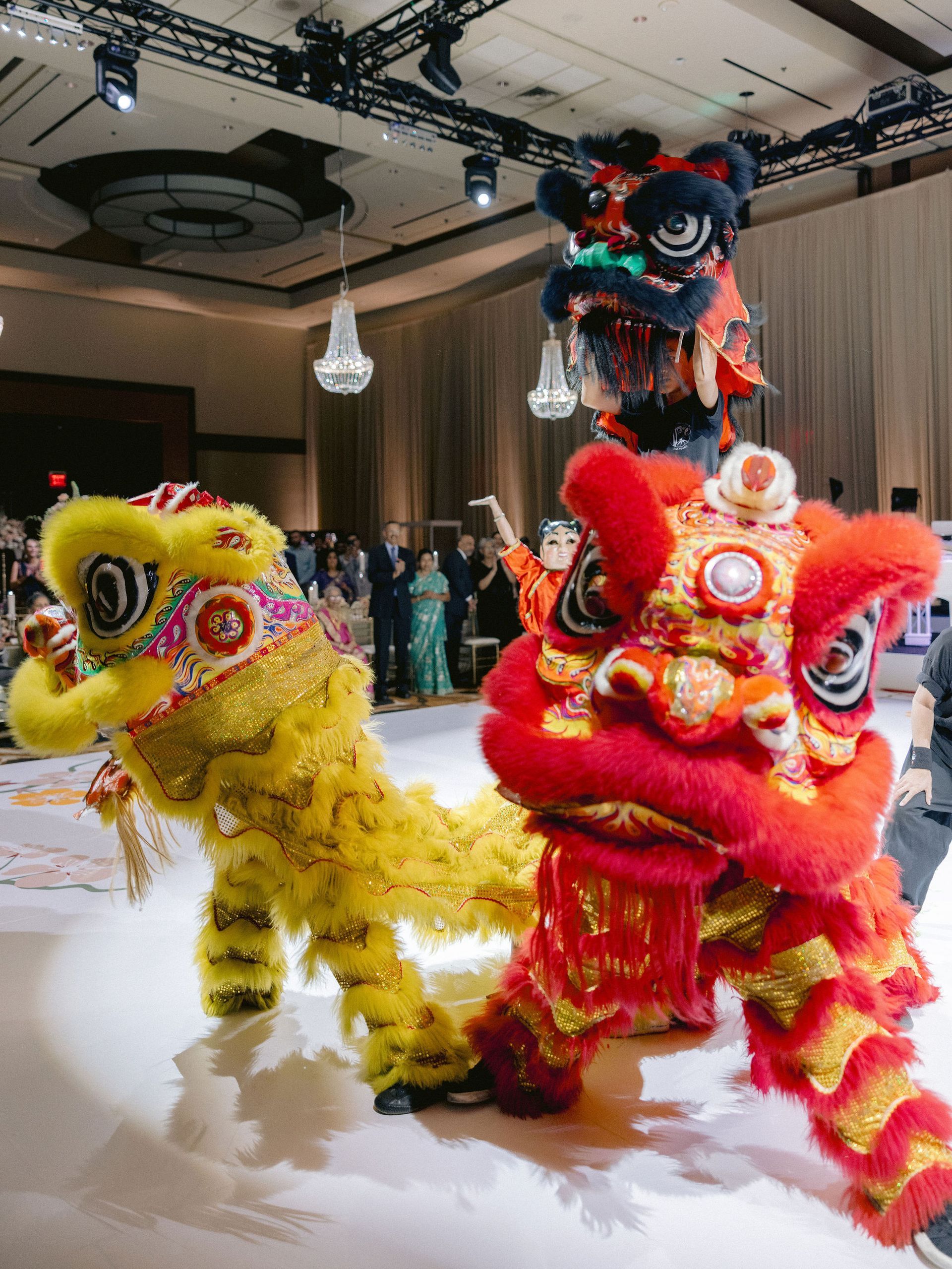 A group of lion dancers are dancing in a large room.