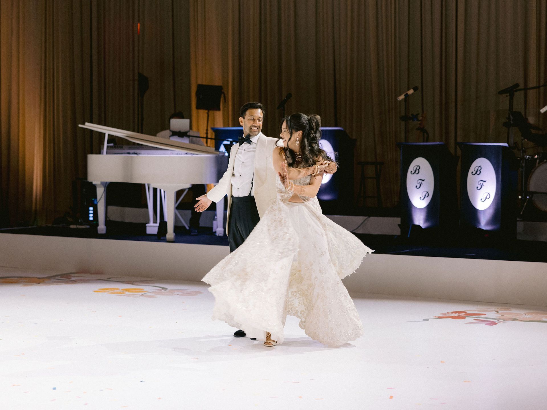 A bride and groom are dancing on a white dance floor.
