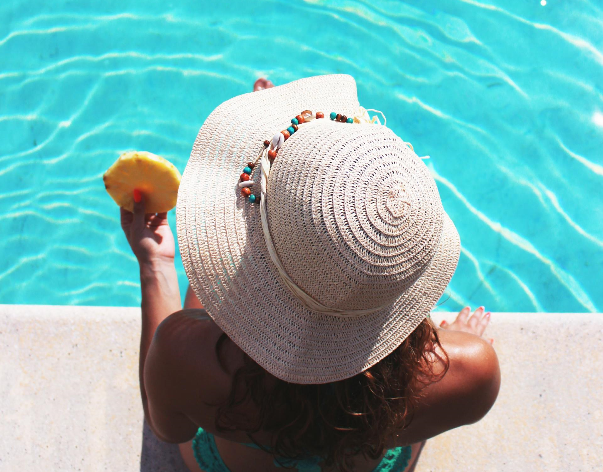Woman in hat sitting beside a pool