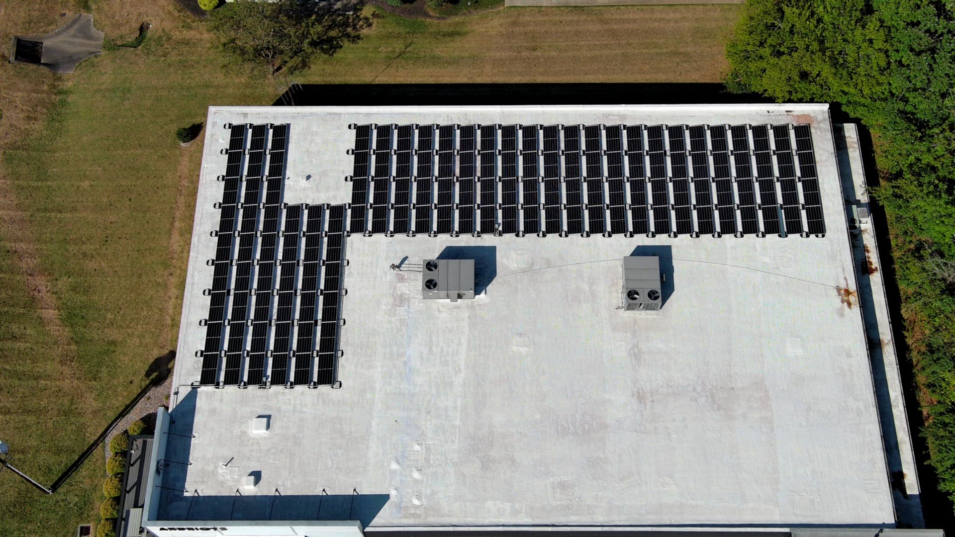 Overhead view of a flat commercial roof with solar panels installed in a grid.