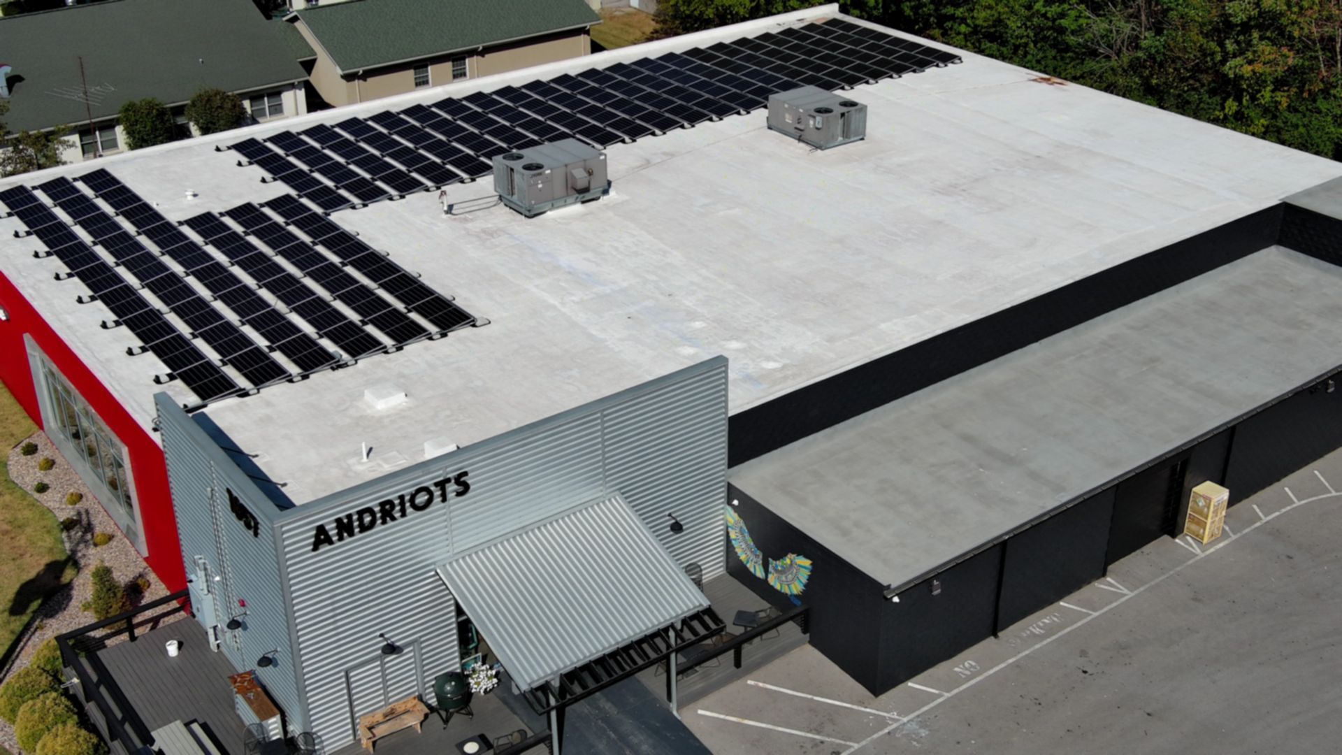 A commercial building with solar panels on the roof. The building has red, gray, and white elements.