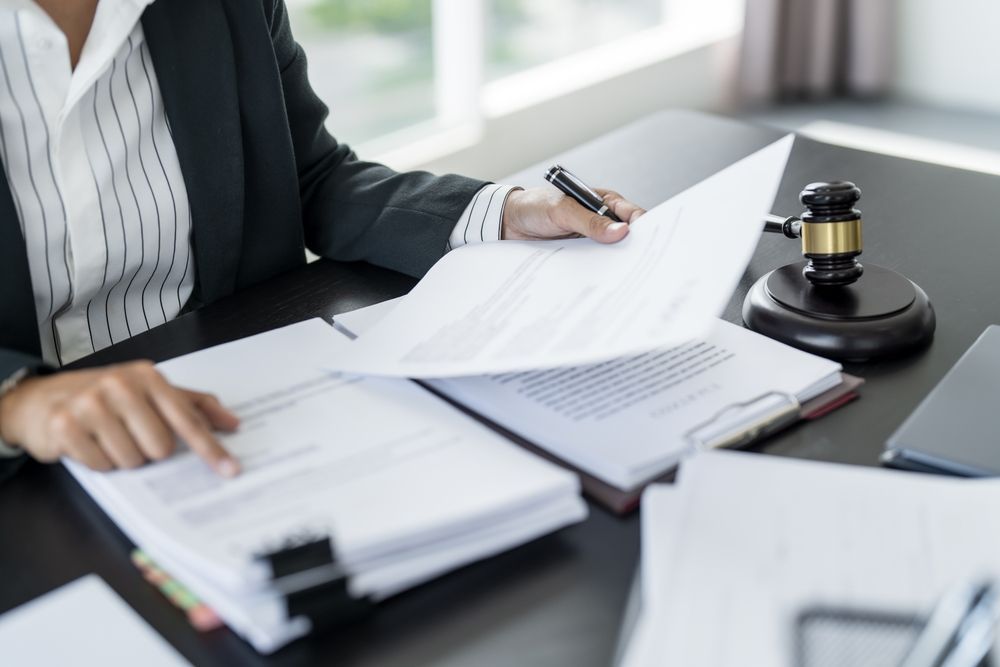 A woman is sitting at a desk with papers and a judge 's gavel.