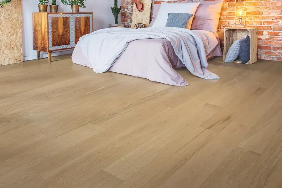 Bright bedroom with a white bed, wooden furniture, and light wood flooring