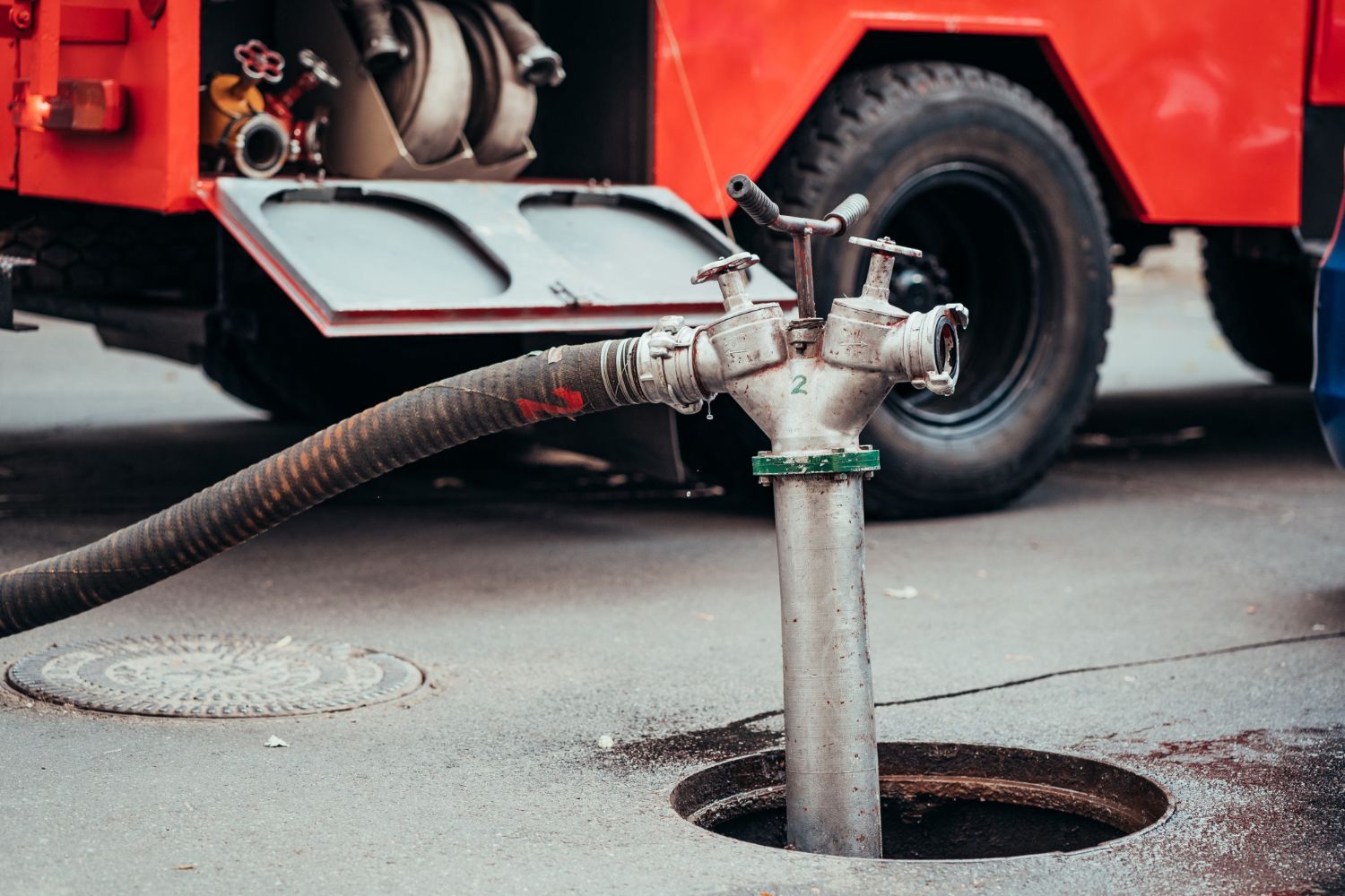Fire truck hose pumping water from a street manhole at an underground fire scene