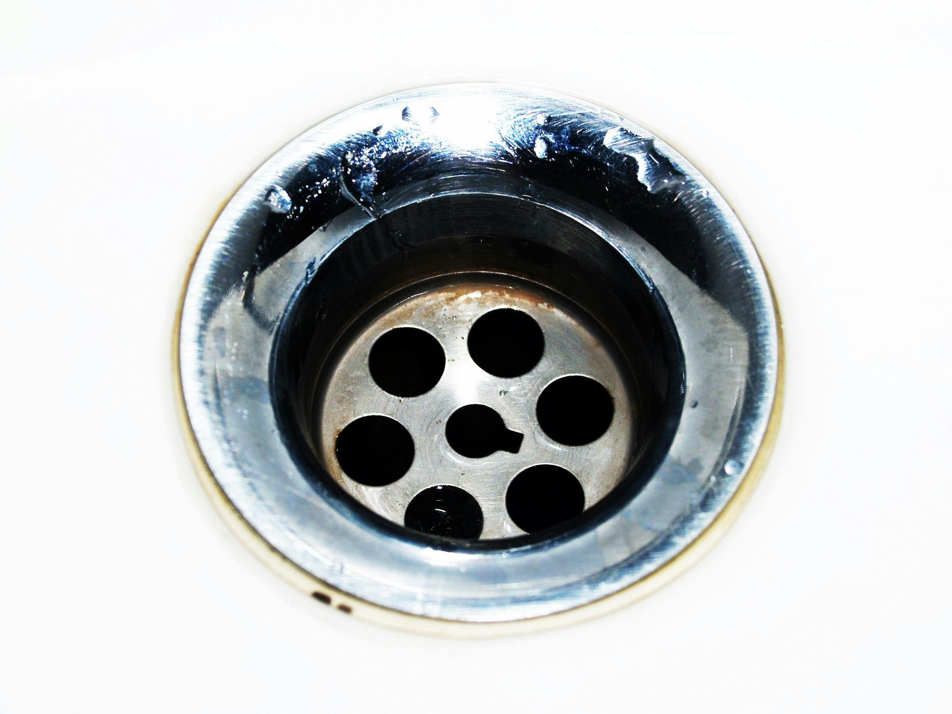 Close-up of a metal sink drain with a perforated stopper opening
