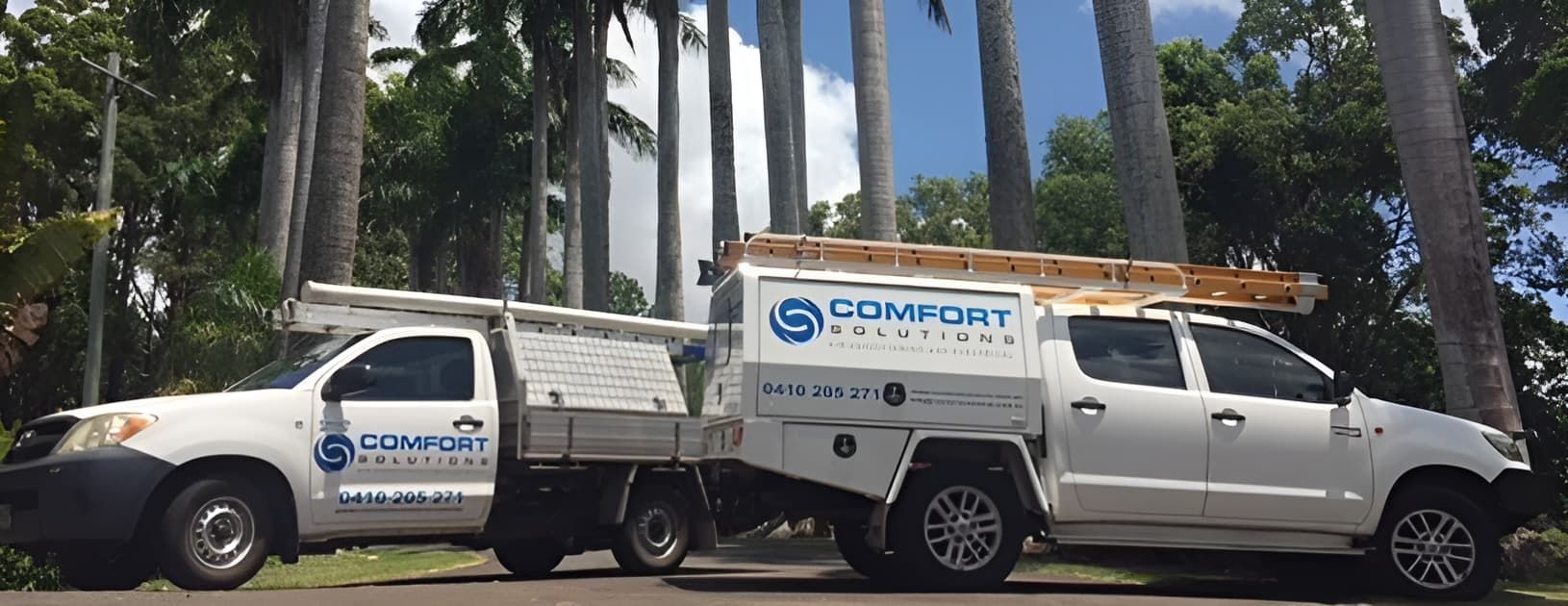 Two White Trucks Are Parked Next to Each Other on the Side of the Road — Comfort Solutions in Kunda Park, QLD
