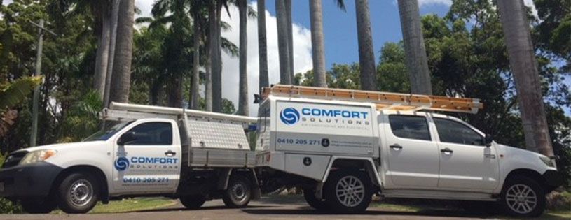 A Man is Sitting on the Ground Working on an Air Conditioner — Comfort Solutions in Kunda Park, QLD