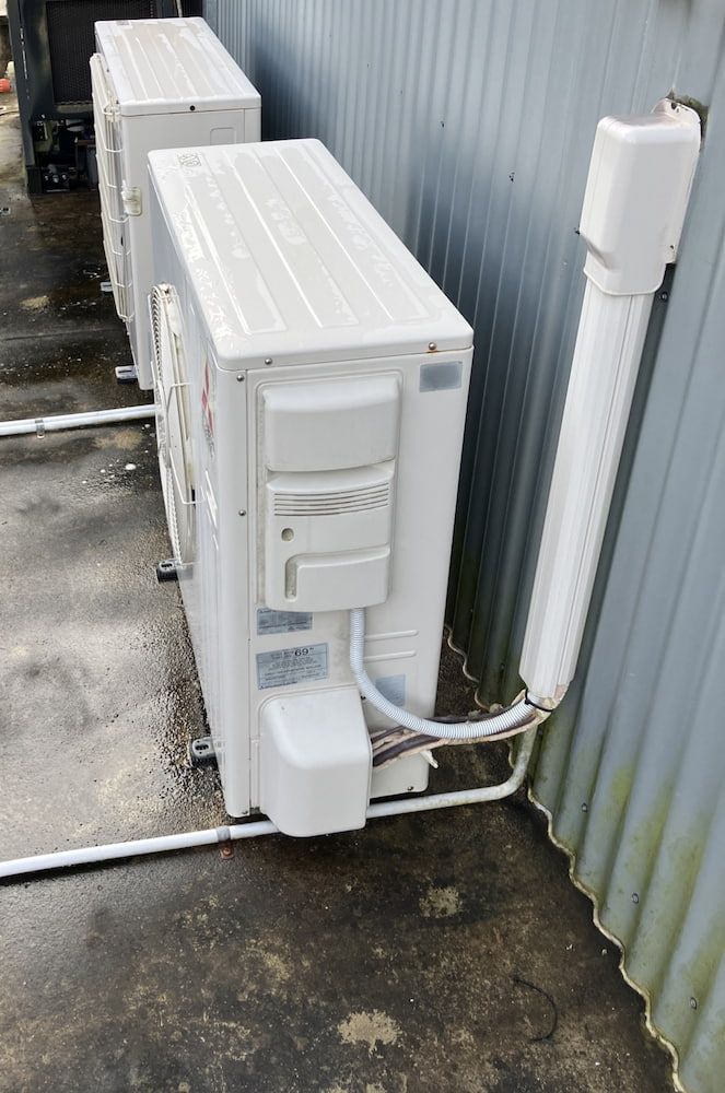 Two Air Conditioners Are Sitting Next to Each Other — Comfort Solutions in Maroochydore, QLD
