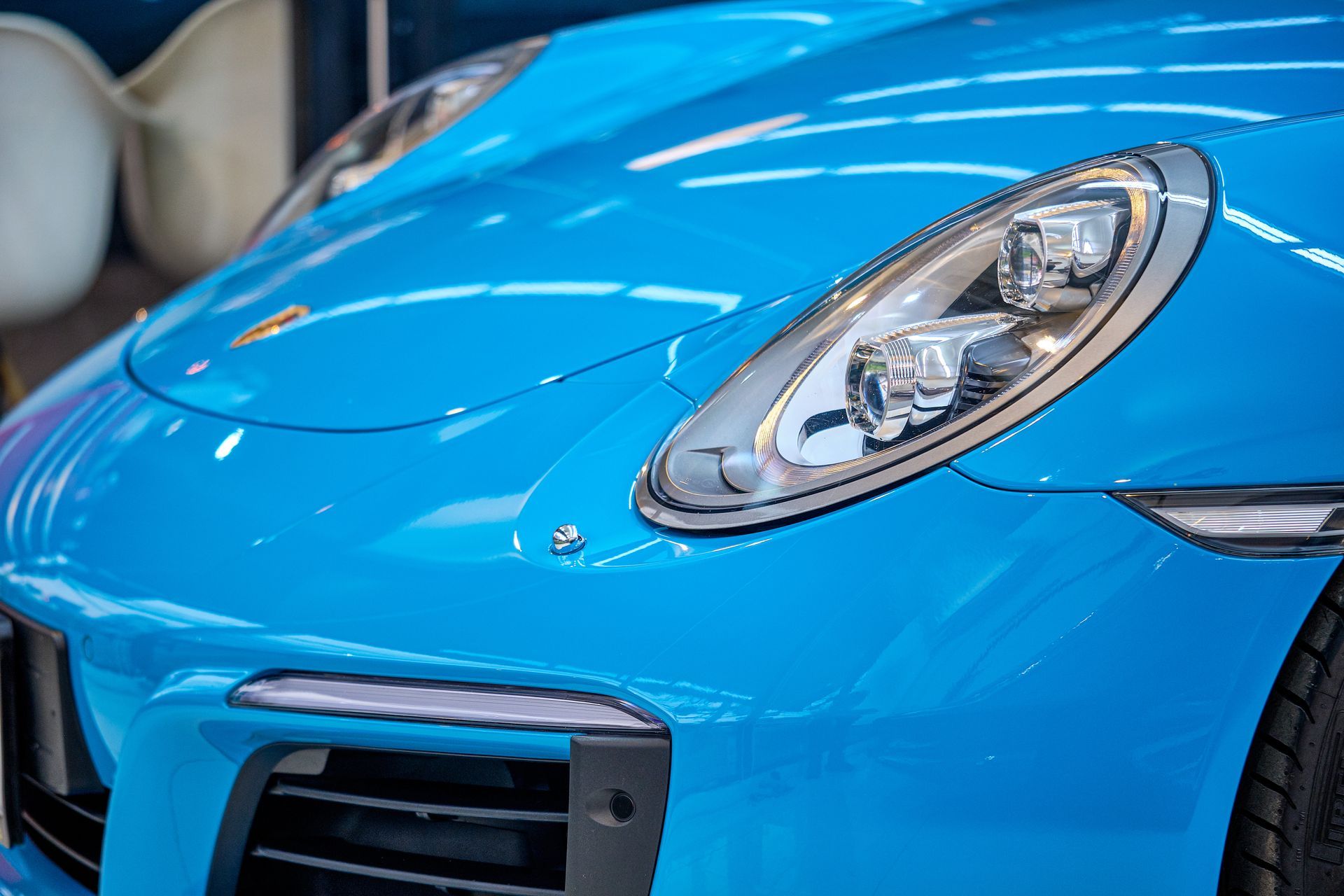 A blue porsche 911 is parked in a showroom.