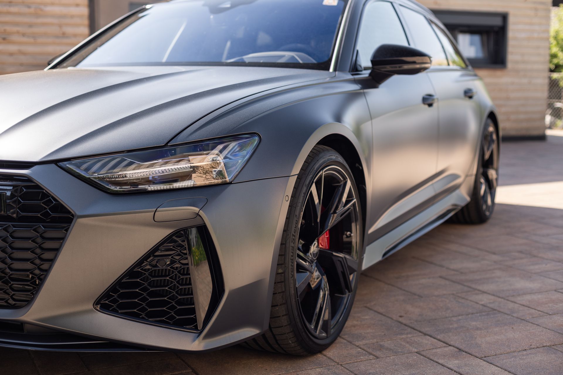 A close up of a black car parked in front of a house.