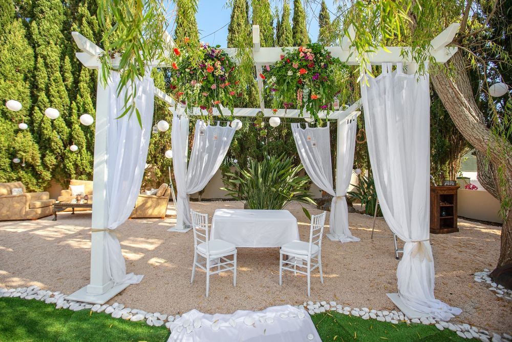 There Is a Table and Chairs Under a Pergola Decorated With Flowers - Yeppoon Balloons & Party Supplies in Yeppoon, Qld