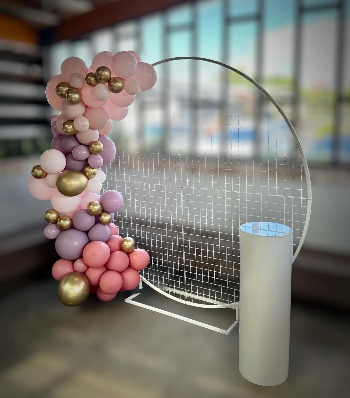 A Balloon Arch is Sitting Next to a White Cylinder in a Room — Yeppoon Balloons & Party Supplies in Yeppoon, QLD