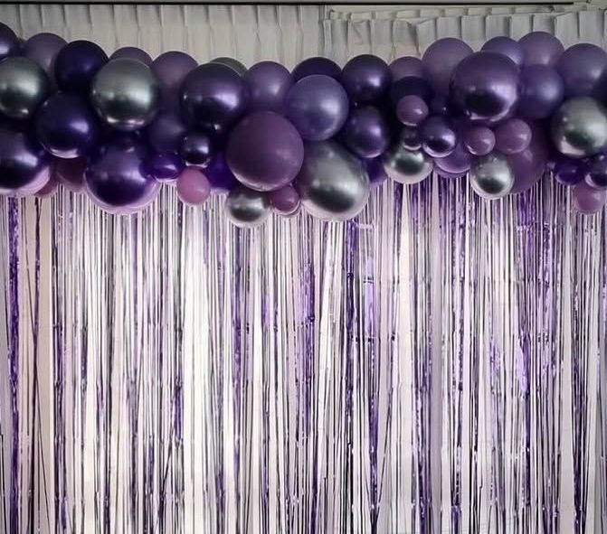 A Bunch of Purple and Silver Balloons are Hanging from a White Curtain - Yeppoon Balloons & Party Supplies in Yeppoon, QLD