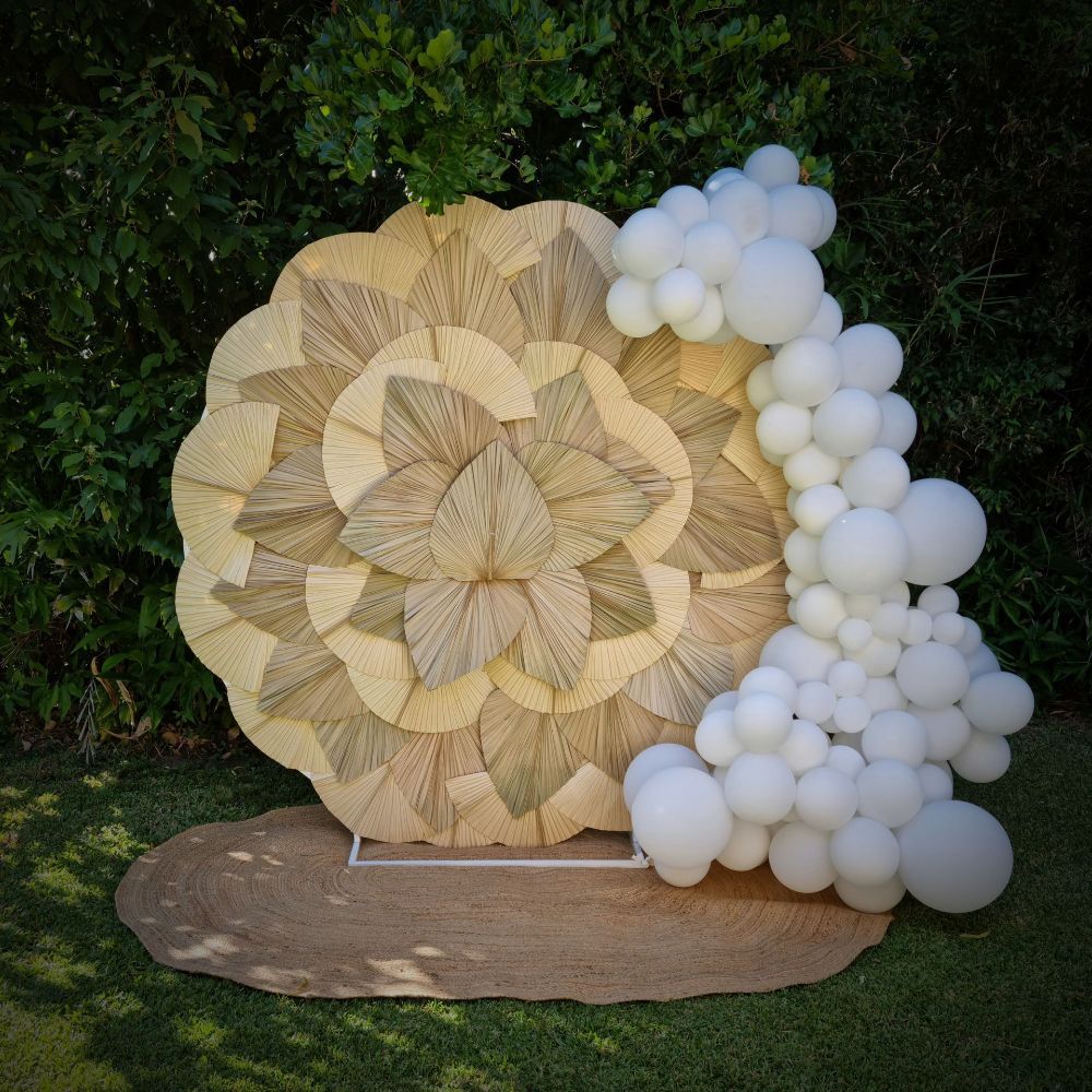 a Palm leaf backdrop with balloons on the side
