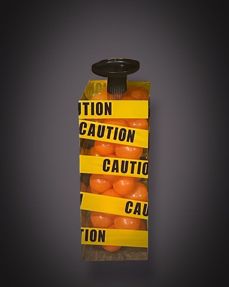A Cake stand designed to look like an explosive with caution tape and balloons inside